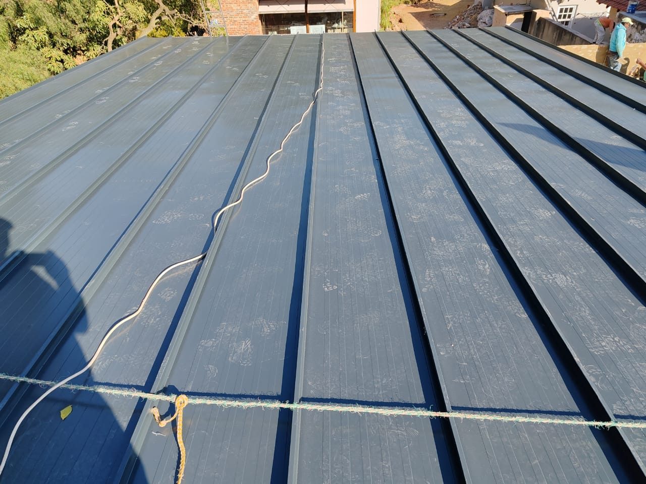 Standing-seam roof close up: continuous runs down the slope, upstand seams, protective film still on the pans. Worth squinting at how few joints there are in the weather surface.