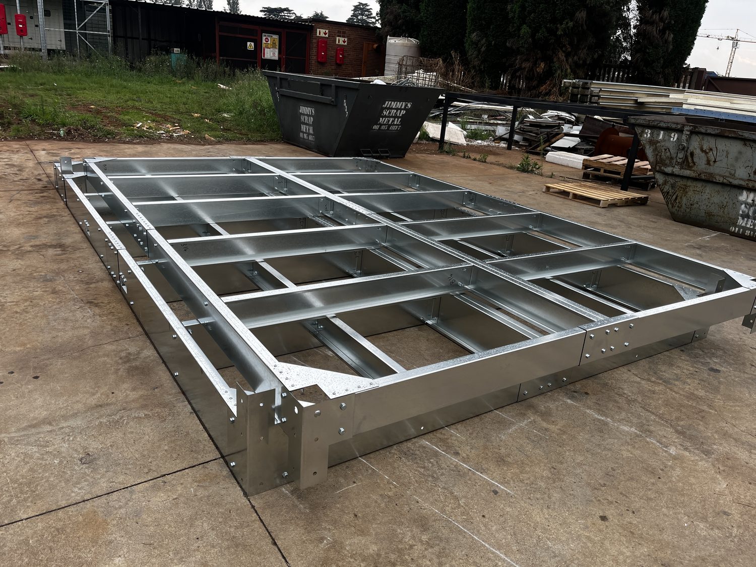 The floor cassette: bolted cold-formed channel joists inside a deep perimeter beam. Every connection is bolted, not welded, and the sections are roll-formed in-house — that is what allows the unit to be a rigid box before any panel goes on.