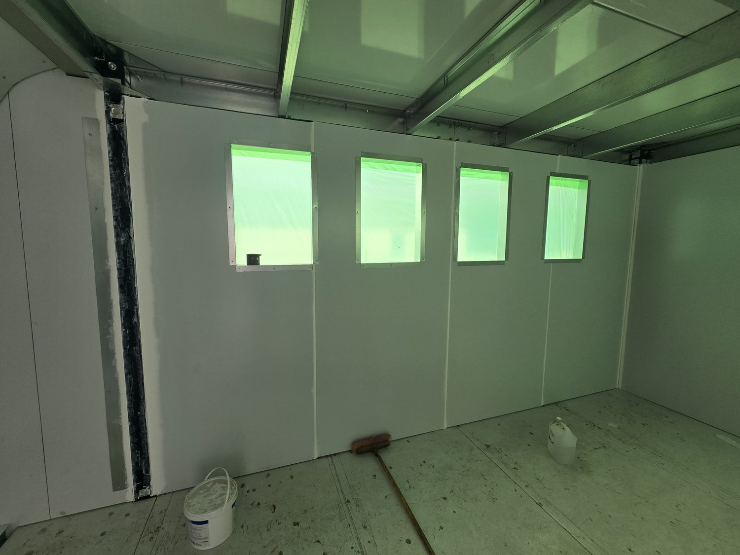 Inside, before fit-out. The wall is the LiteSpan panel — no stud, no board, no plaster. Window openings are cut in the panel and trimmed with a steel liner; the cold-formed roof beams sit above the panel head.