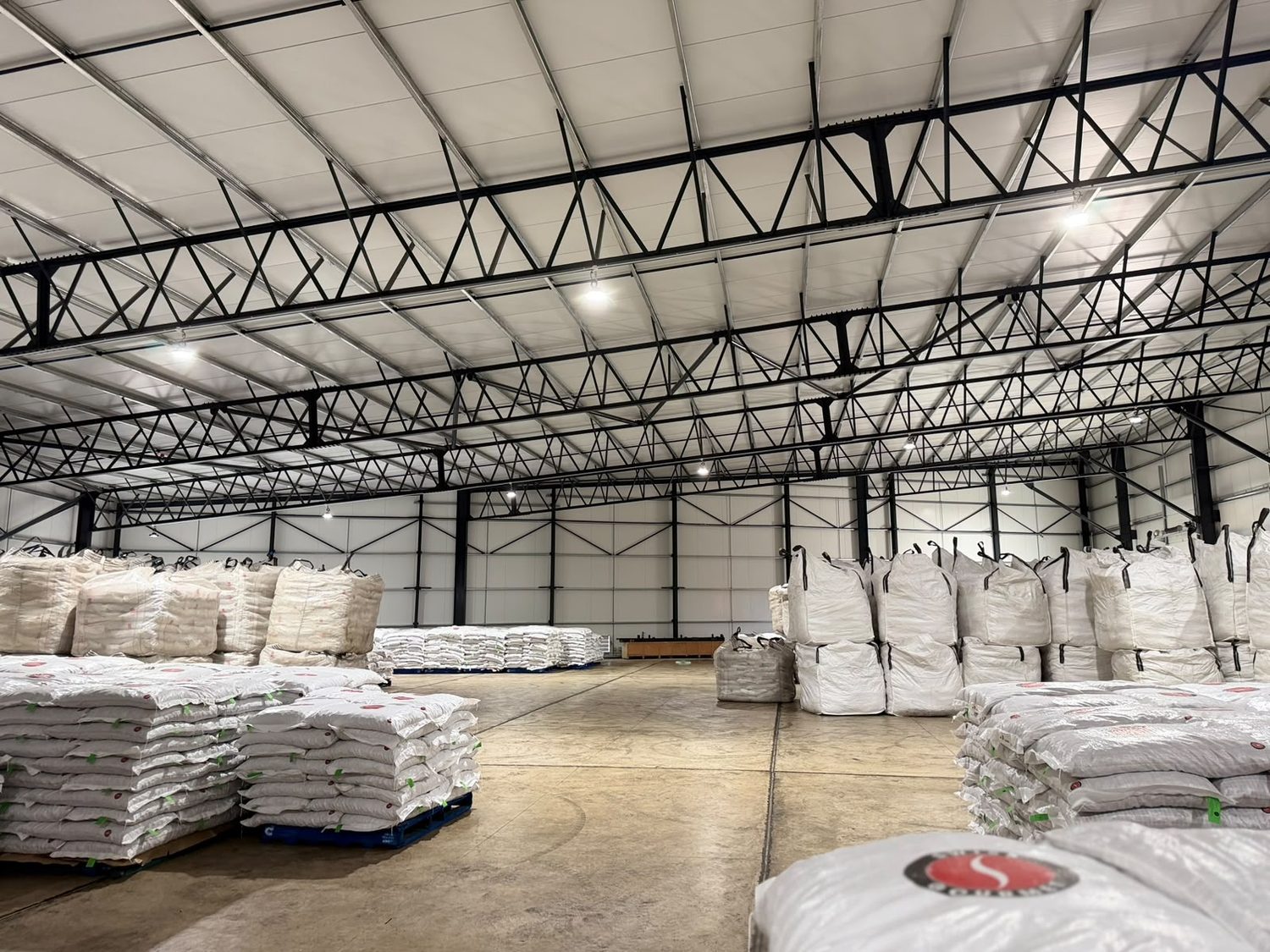 The same volume in service, stacked with bagged and bulk-bagged product. Notice that the panel is the working surface: it is what the pallets stand against, what the forklift passes and what gets swept. It arrived finished, and it stayed the finish.