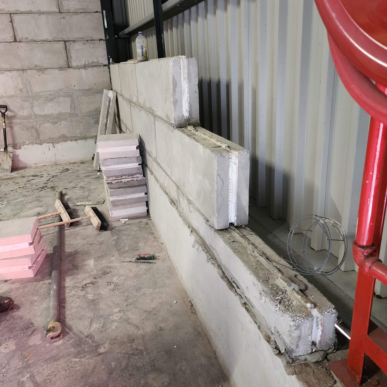 The section, on site. The end of the block shows the 150 mm composite - two foamed-cement skins with the white EPS core between them - and the tongue-and-groove bed it sits on. Note the thin bed of adhesive, not a mortar joint.