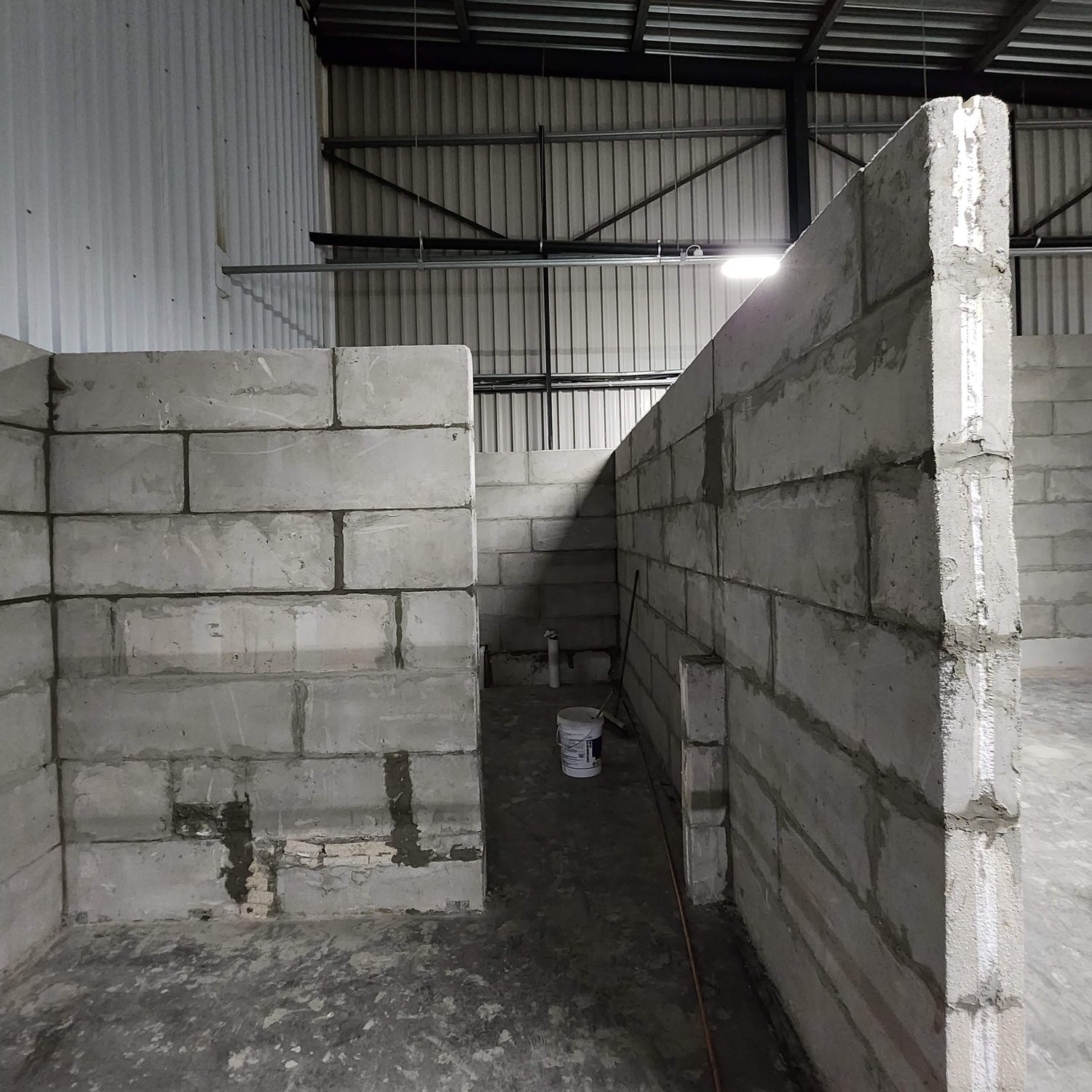 Bare walls inside the shed: 1200 x 340 mm coursing, freestanding between the steel columns, stopping clear of the roof. This is what non-load-bearing infill looks like before it is rendered.