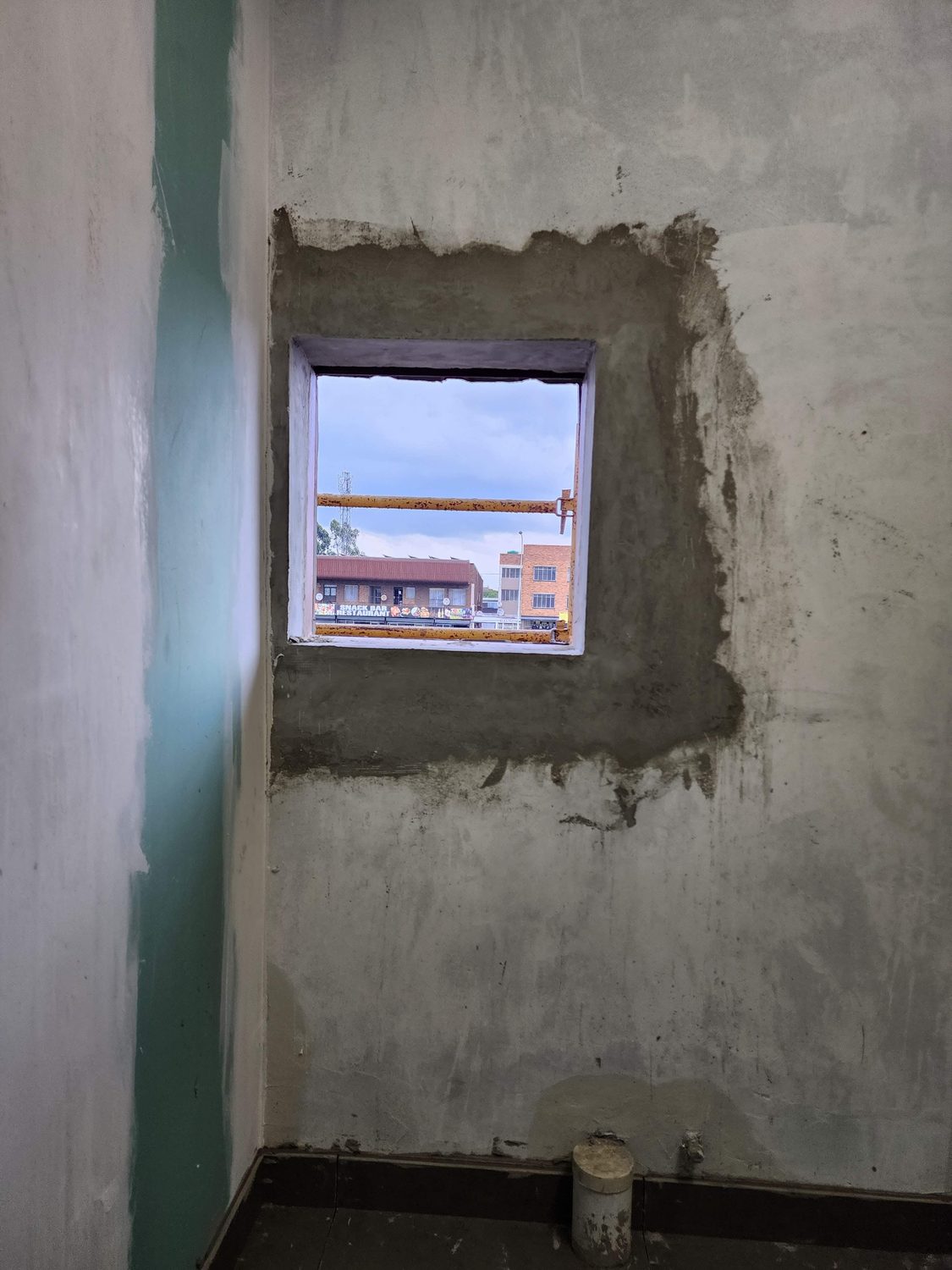 A window opening part-rendered. The reveal shows the through-thickness of the wall and the render coat going on over the block face - the finish is conventional plaster, not a proprietary board system.