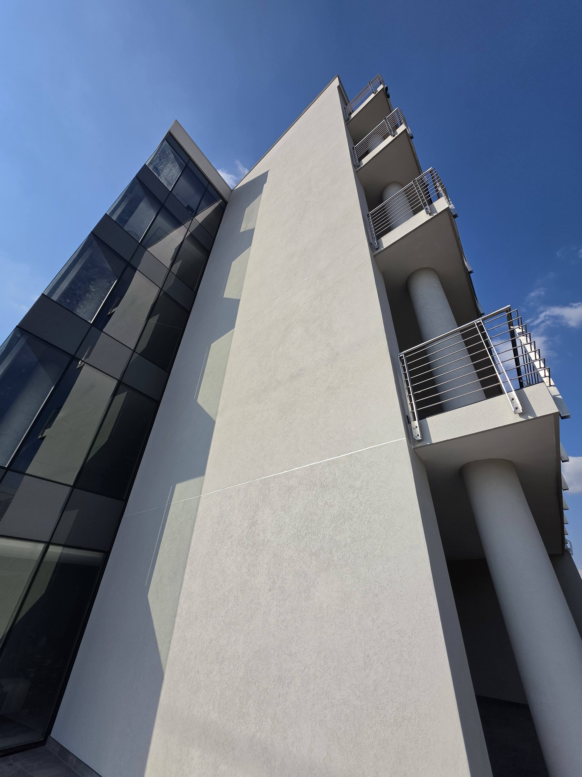 Looking up the corner where the coated plane meets the glazed stair. The finish turns the angle as one surface, and the only lines in the face are the scored joints.
