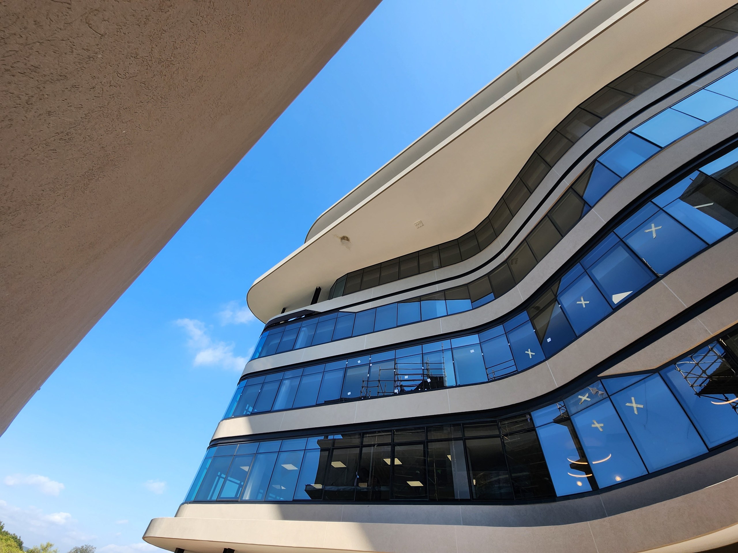 Looking along the curved elevation. The rendered bands run away from the camera round the curve without a break or a joint line; the textured render soffit fills the top left of the frame.