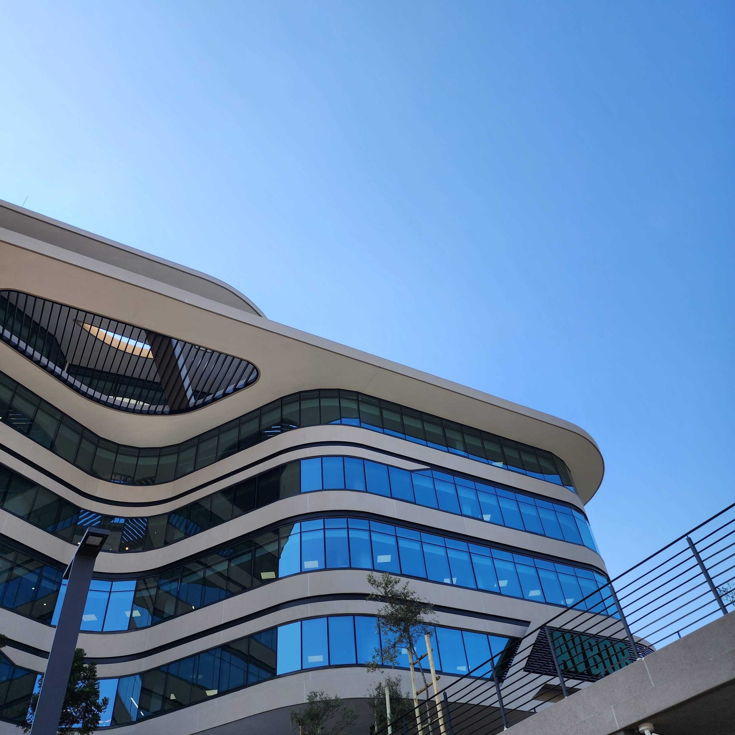 The upper floors from below. Each band turns through the plan curve as a single rendered surface, and the louvred oculus is cut into that same surface with a radiused rendered reveal.