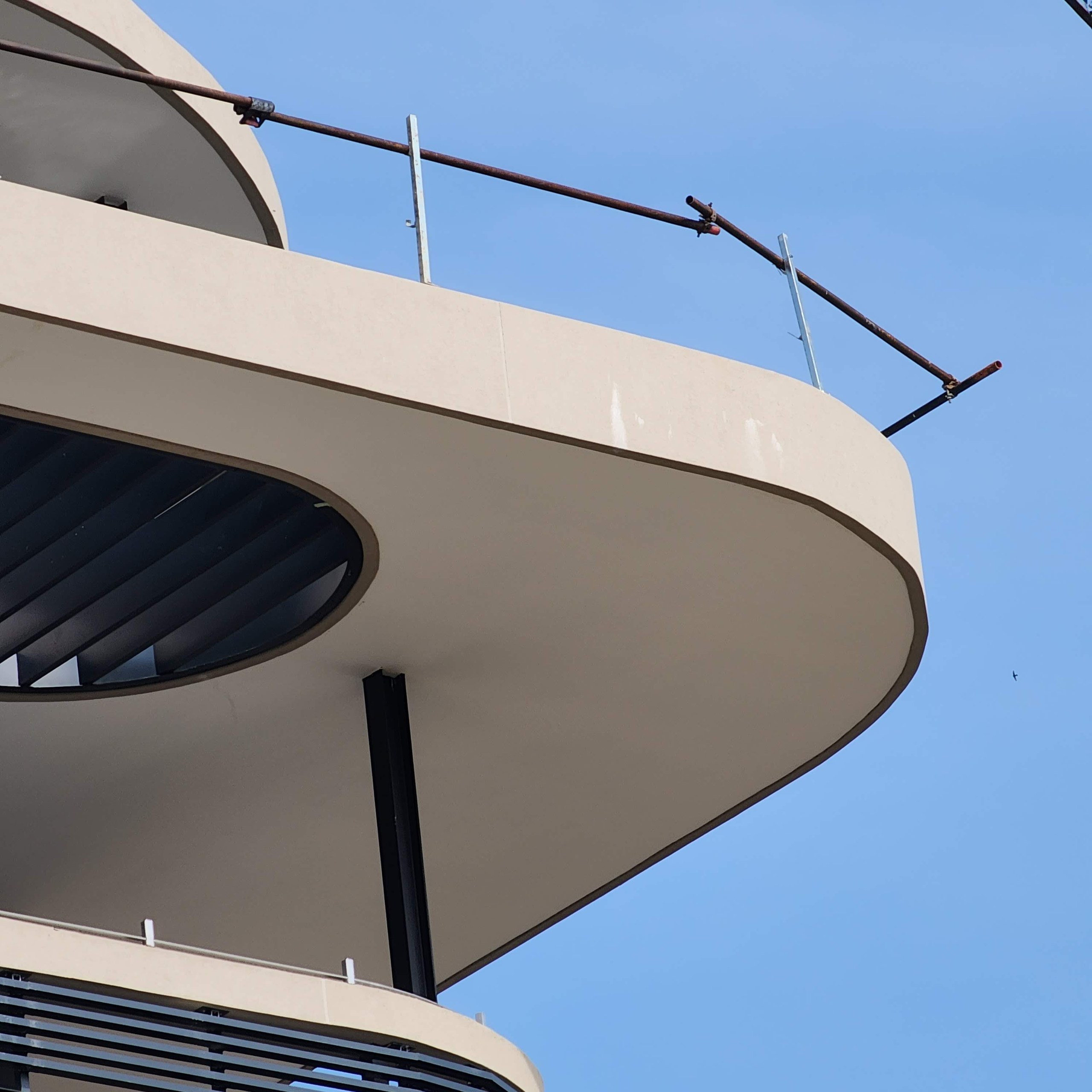 The nose of a floor plate. The rendered fascia turns through the full radius and continues underneath as the soffit - one surface, with no joint at the turn.