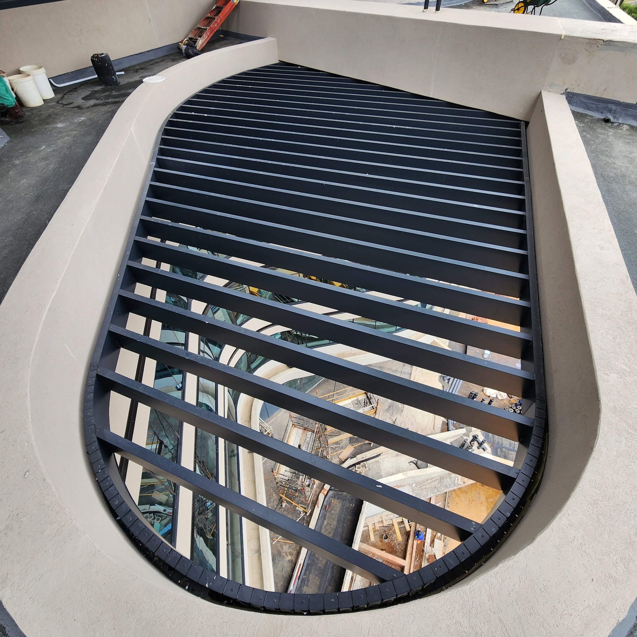 One of the louvred oculi seen from the terrace above. The opening is rendered to a continuous radiused reveal all the way round, so the curve is a finished surface rather than a cut edge.
