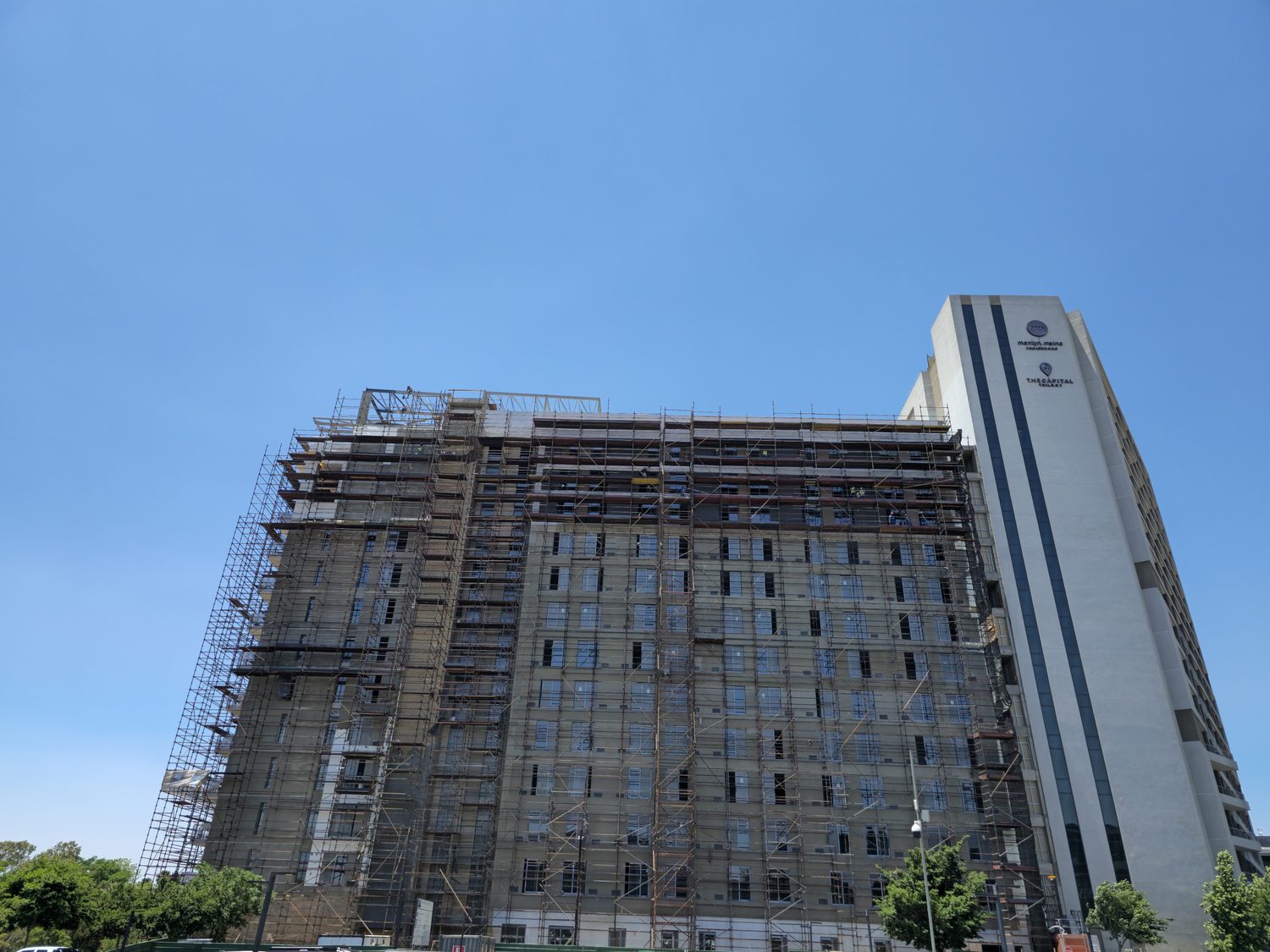 The scale of the job: the whole tower scaffolded out for the facade, with the completed Phase 1 block on the right. Every square metre of that elevation is EPS board, mesh-reinforced basecoat and render, installed from the scaffold in lifts.