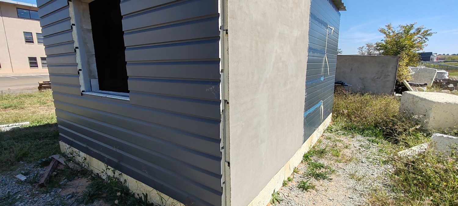 Two Technopol envelopes meeting on one box: LiteClad weatherboard on the near elevation, rendered finish on the return. Note the window opening is cut straight through the cladding and the boards die into the reveal without a face trim.