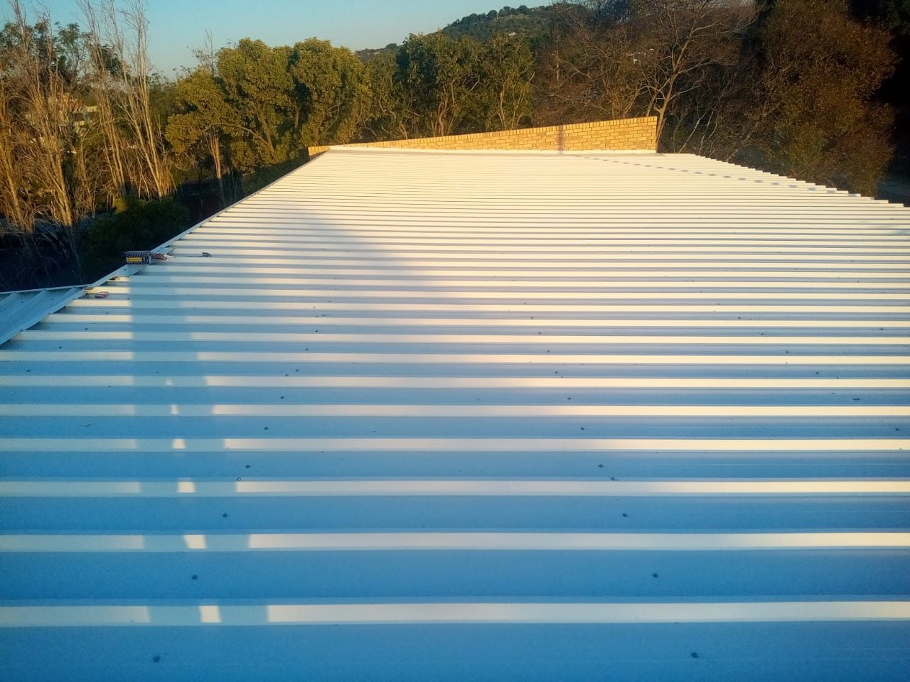 The finished roof plane. Fixings sit down in the valleys, not on the ribs, and the side laps run unbroken up the slope — the fastener pattern to check on a 990 IBR.