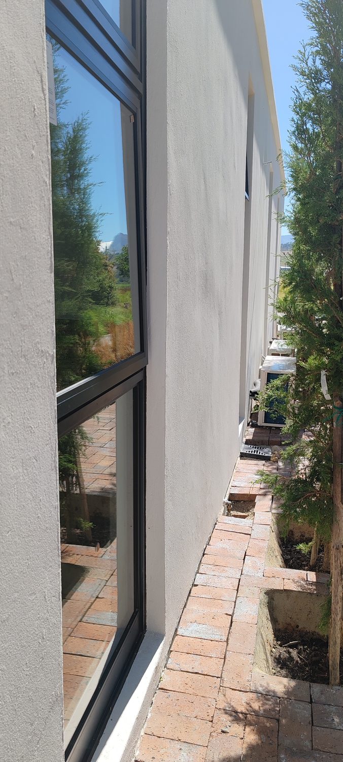 The junction a specifier squints at: the reinforced render returns into the reveal and dies cleanly against the aluminium frame, with the textured Terraco grain visible across the face. No bead line, no shrinkage crack at the corner.