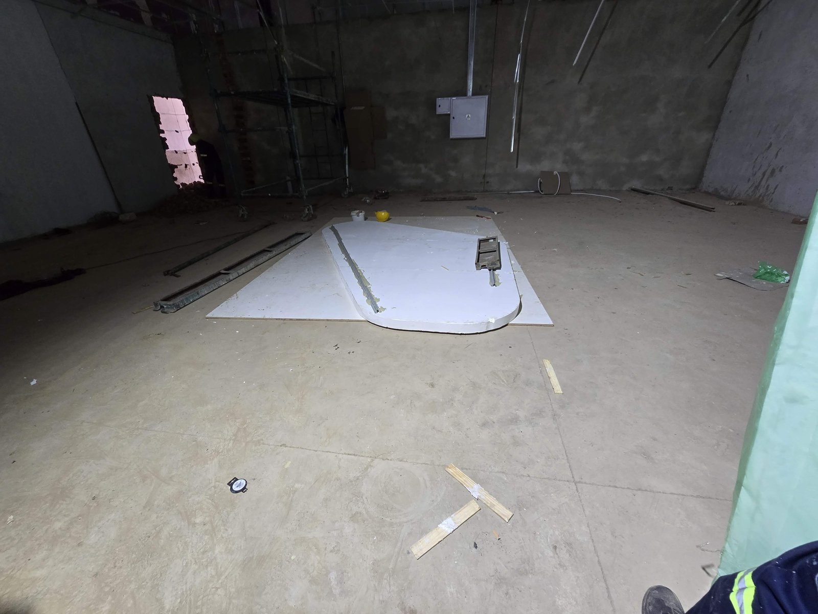 Curved triangular EPS shape cut and laid out on the floor of a bare concrete unit before installation.