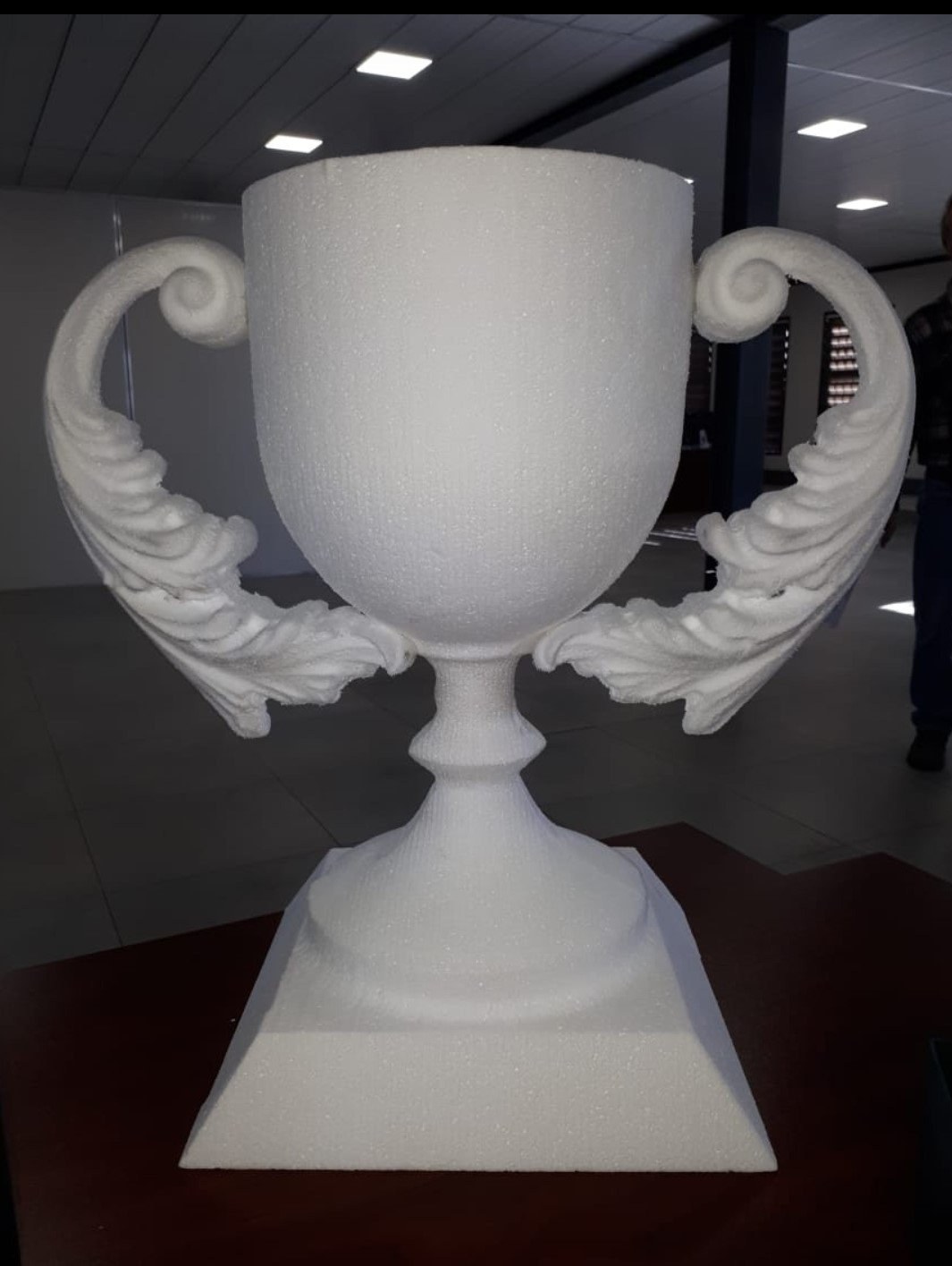 A trophy cup milled in EPS - bowl, turned stem, stepped square plinth and scrolled acanthus handles cut as one sculpted form. Shown unfinished, with the raw bead texture of the foam still visible on every surface.