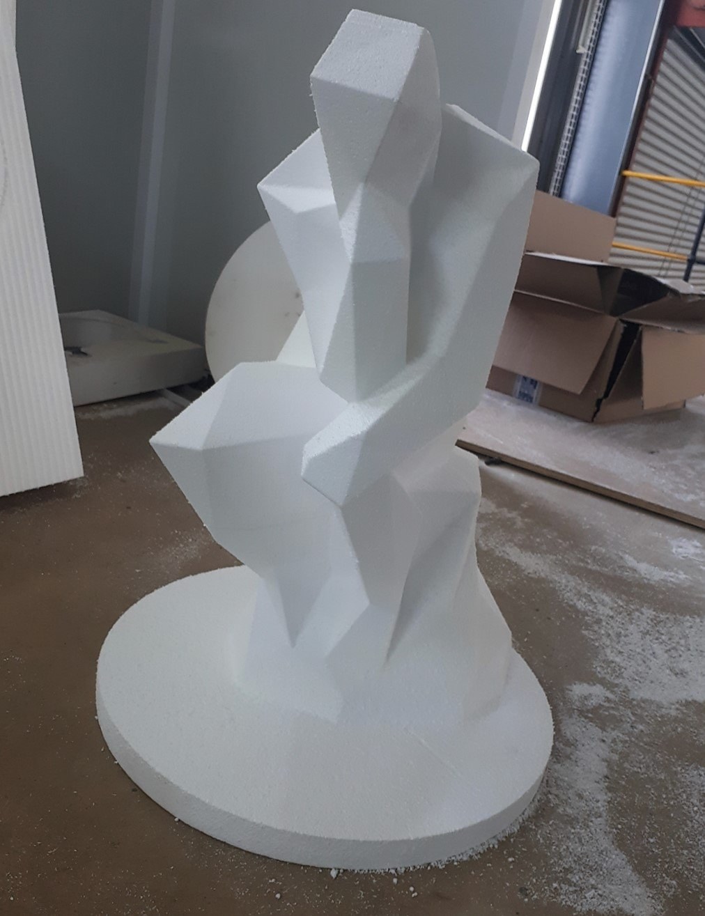 Abstract faceted sculpture on a circular EPS base, workshop floor