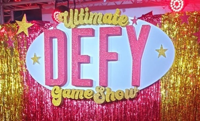 Painted foam letters forming a game-show logo, installed on an event stage backdrop