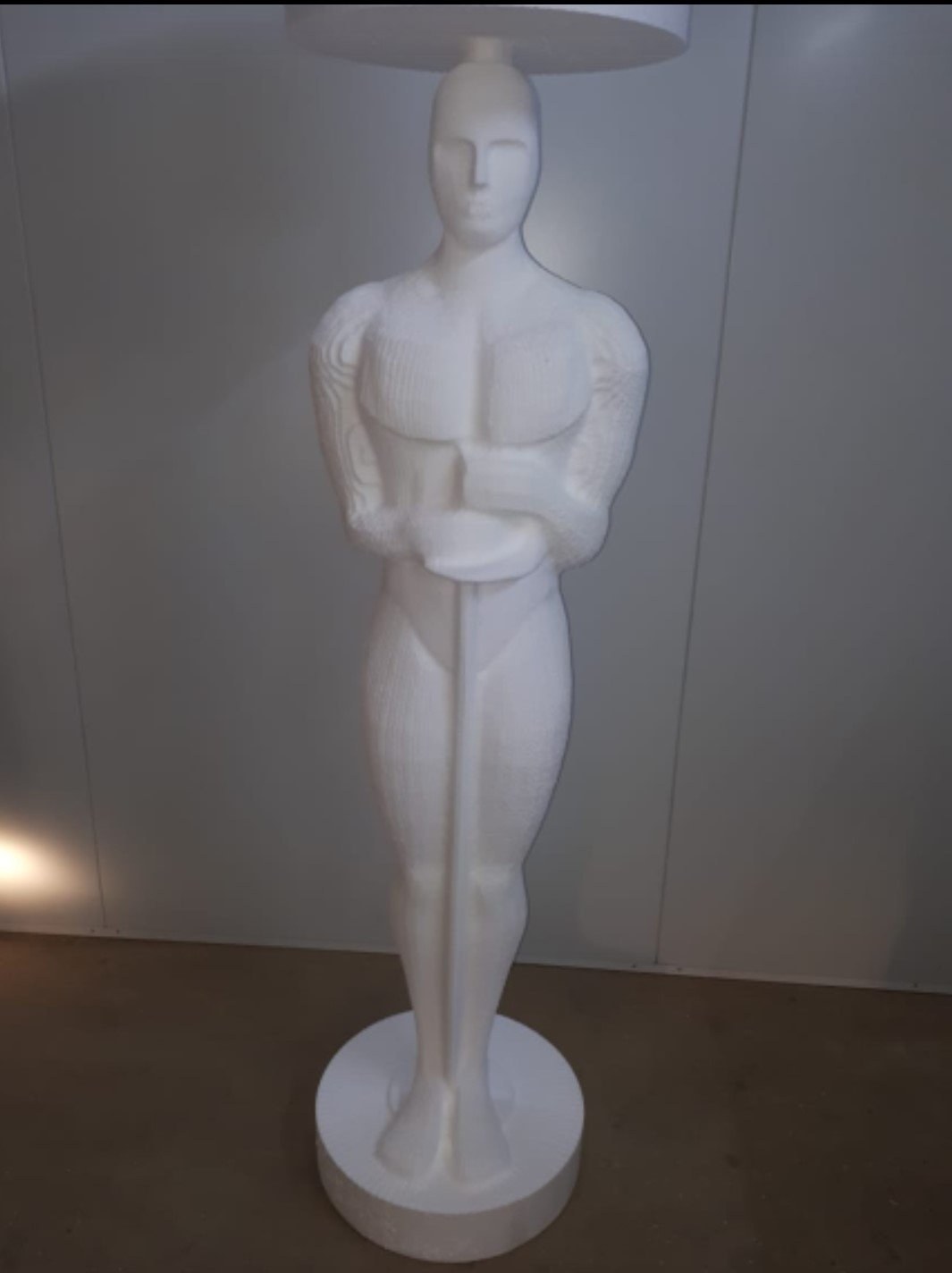 Muscular male figure sculpture used as a lamp base, lampshade visible above
