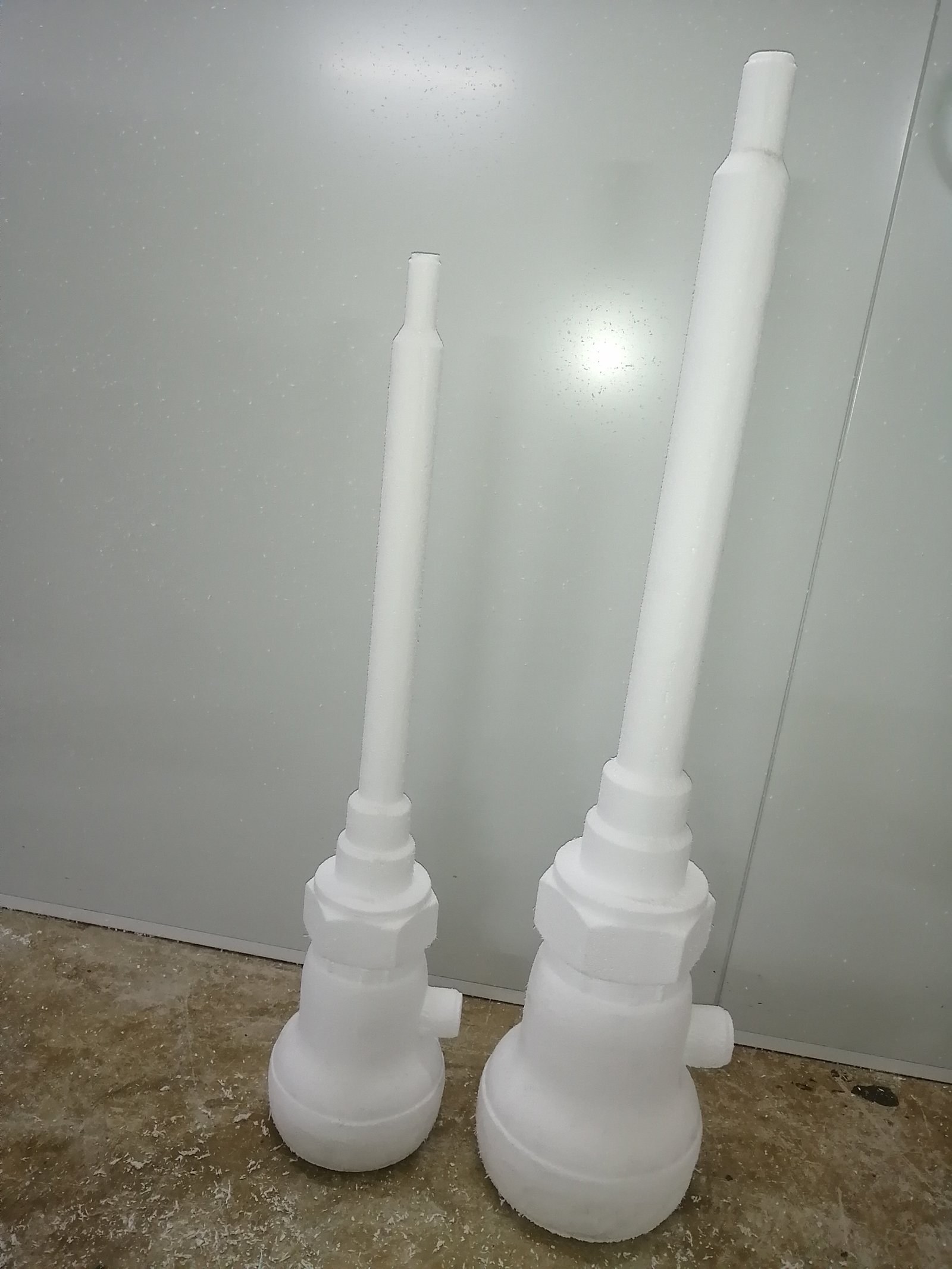 Two oversized valve-shaped props carved from EPS, standing against a workshop wall