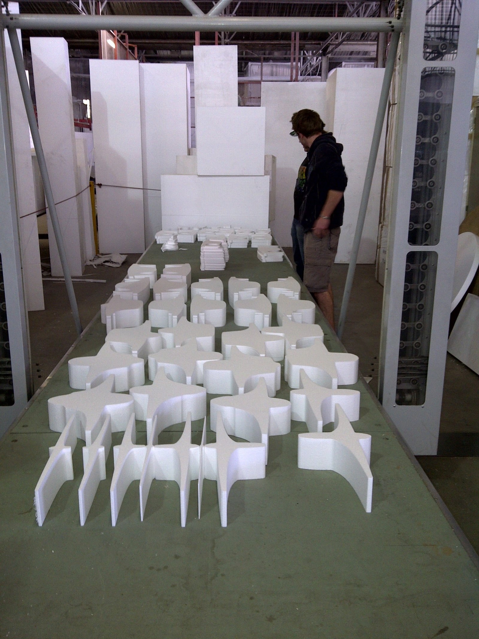 Rows of star- and cross-shaped CNC-cut pieces laid out on a trestle table, worker inspecting the batch