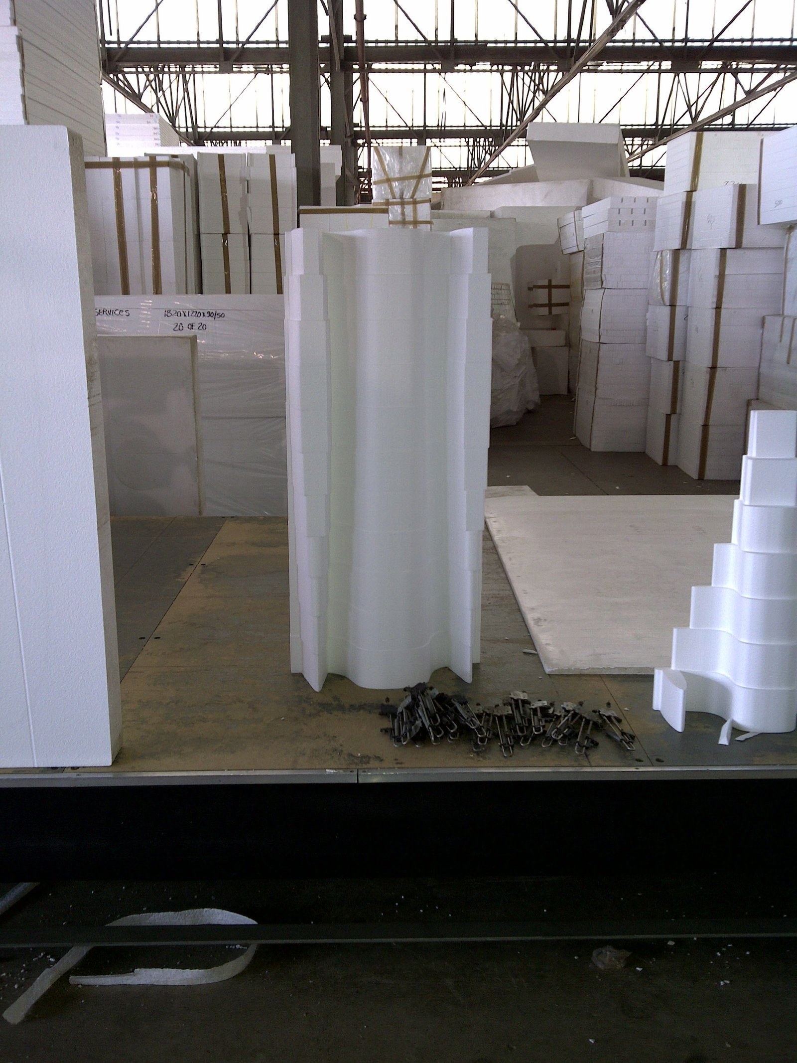 CNC-milled fluted column section stood upright amid stacked EPS board in the factory