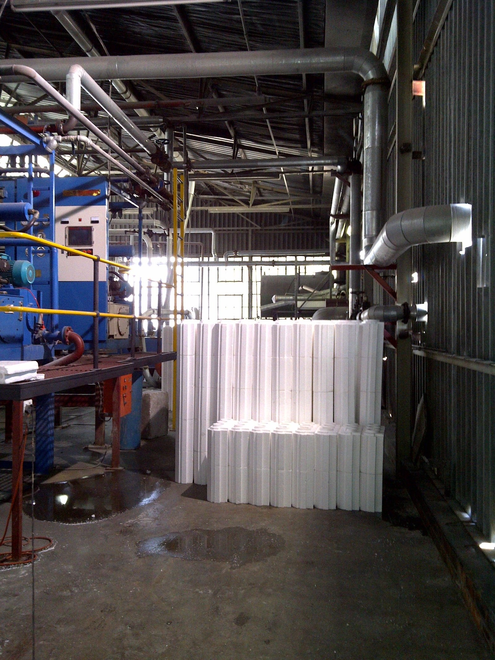 Stack of fluted cylindrical column sections beside factory processing machinery