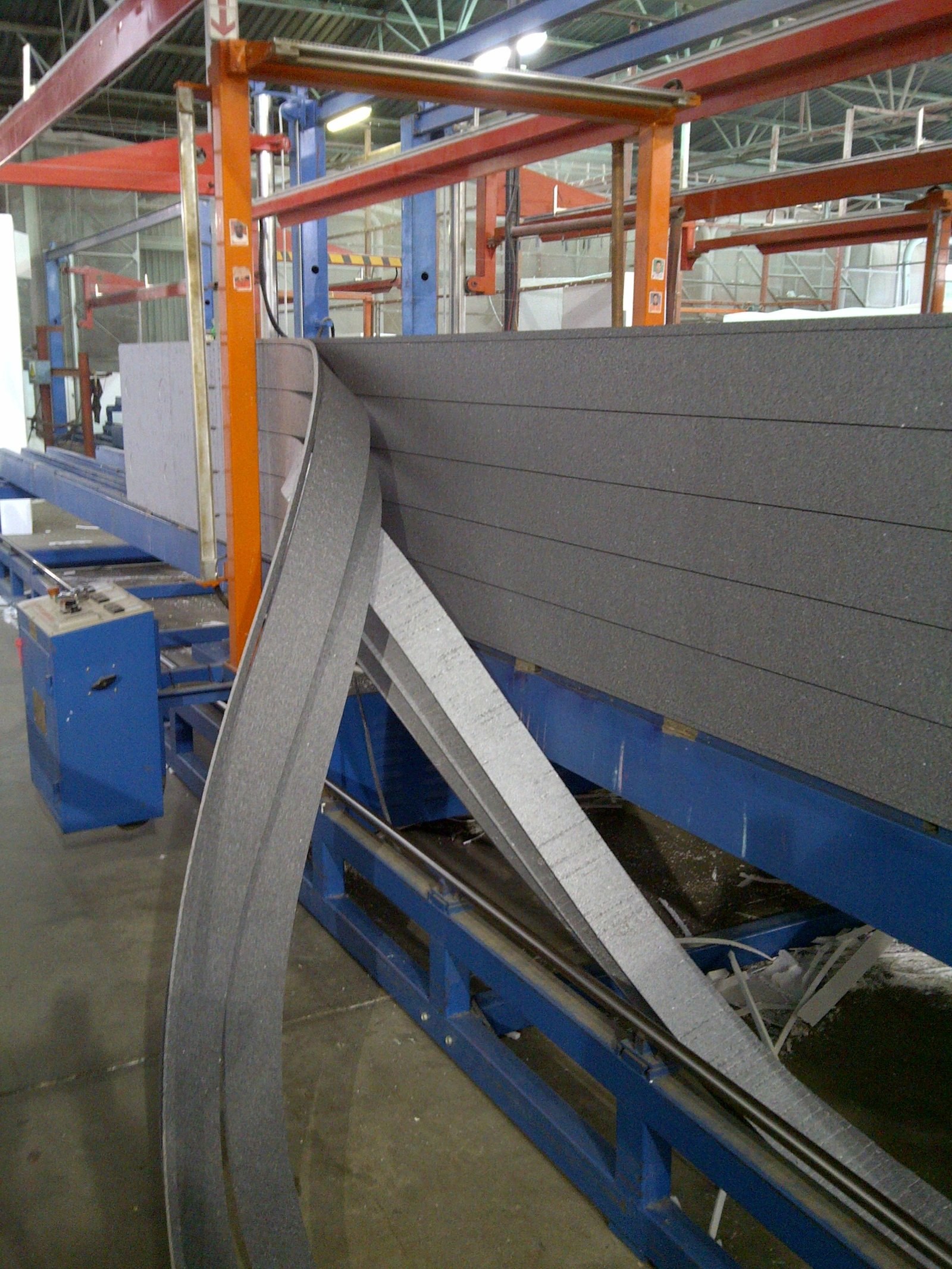 Curved EPS boards, dark graphite-enhanced material, coming off a factory forming line