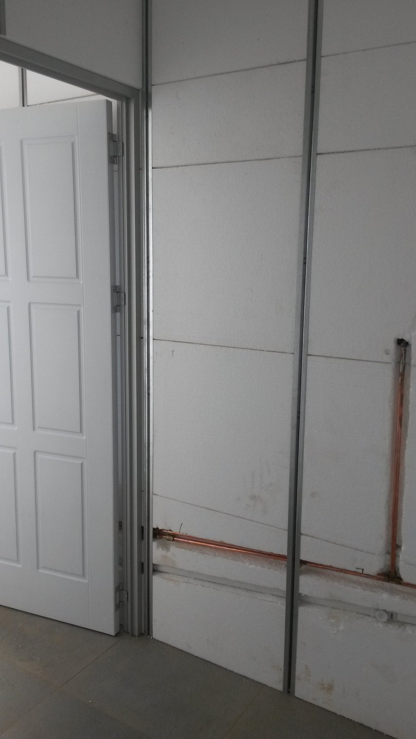 Close-up of an EPS panel joint beside a doorway, with a copper pipe recessed into the board
