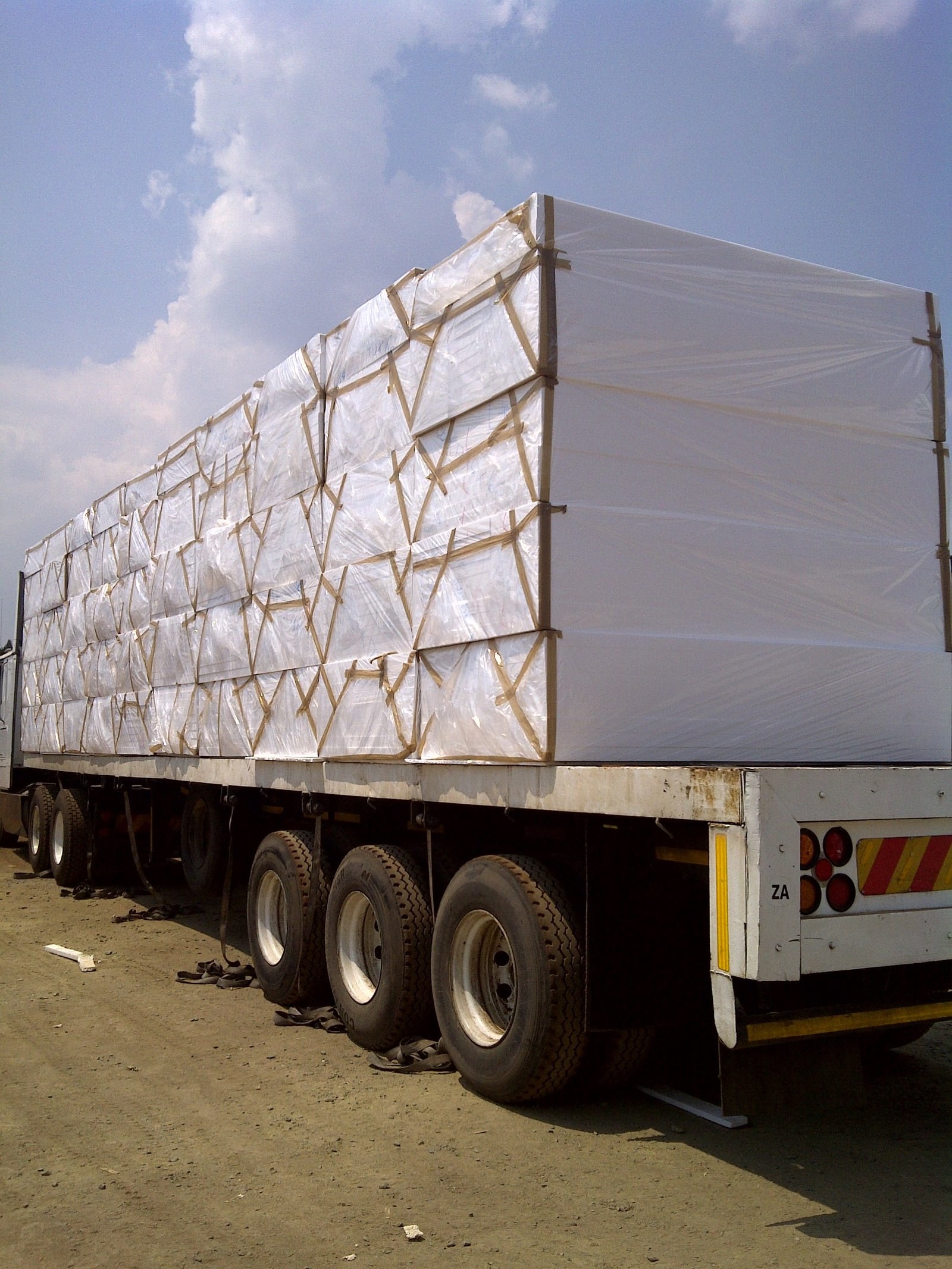 Flatbed truck loaded with wrapped EPS panel bundles