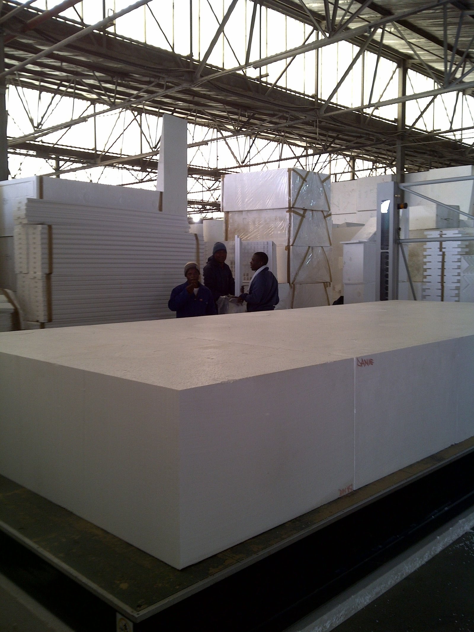 Large EPS block on the factory floor, workers talking in the background