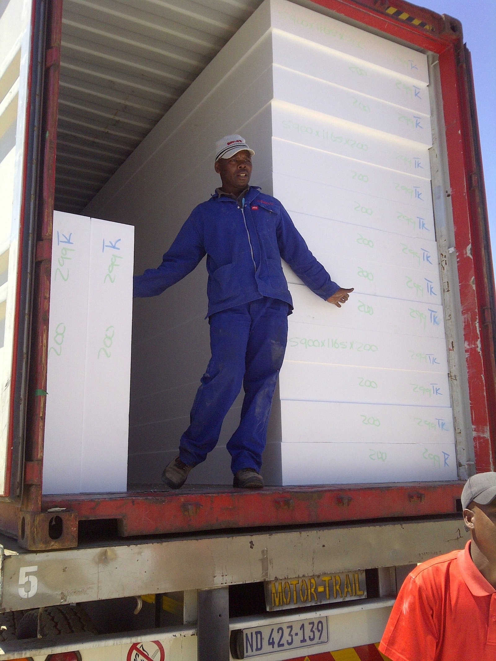 Worker loading marked EPS boards into a shipping container