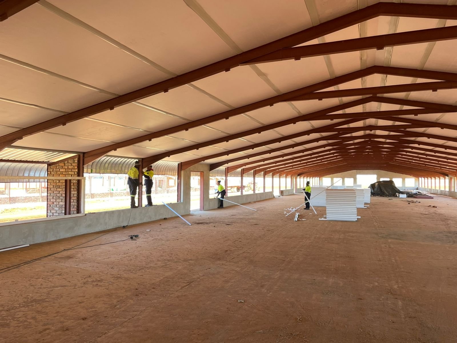 EPS panels staged on the floor of a poultry house under construction, insulated ceiling boards already up