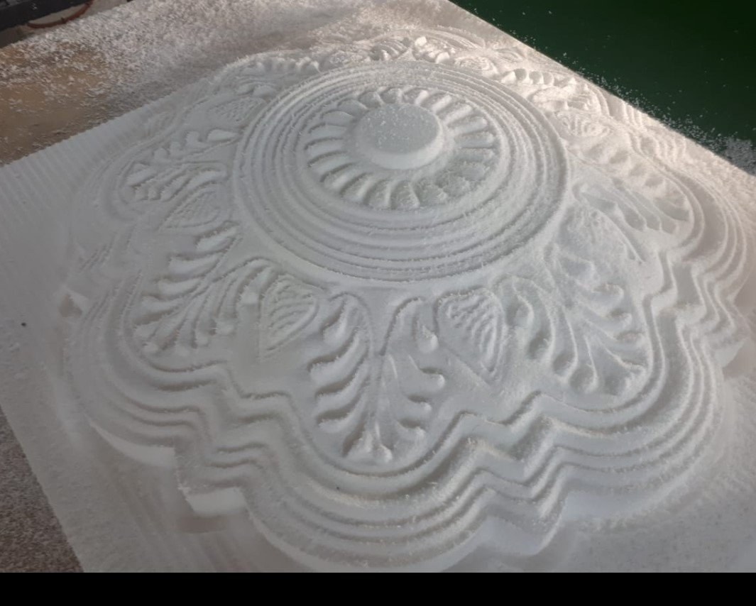 A circular floral relief pattern machined into a white EPS slab, still sitting in the parent block with cutting dust across the surface. Raw and uncoated, straight off the machine bed.