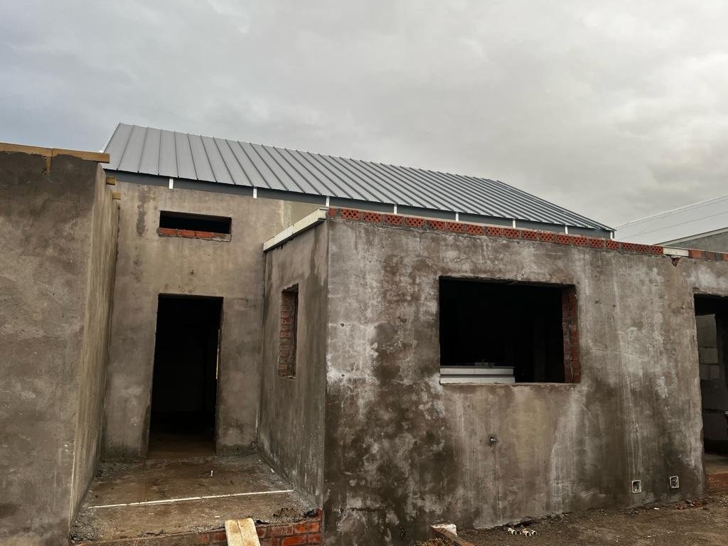 Standing-seam roof sheeting fitted over an unplastered block building shell