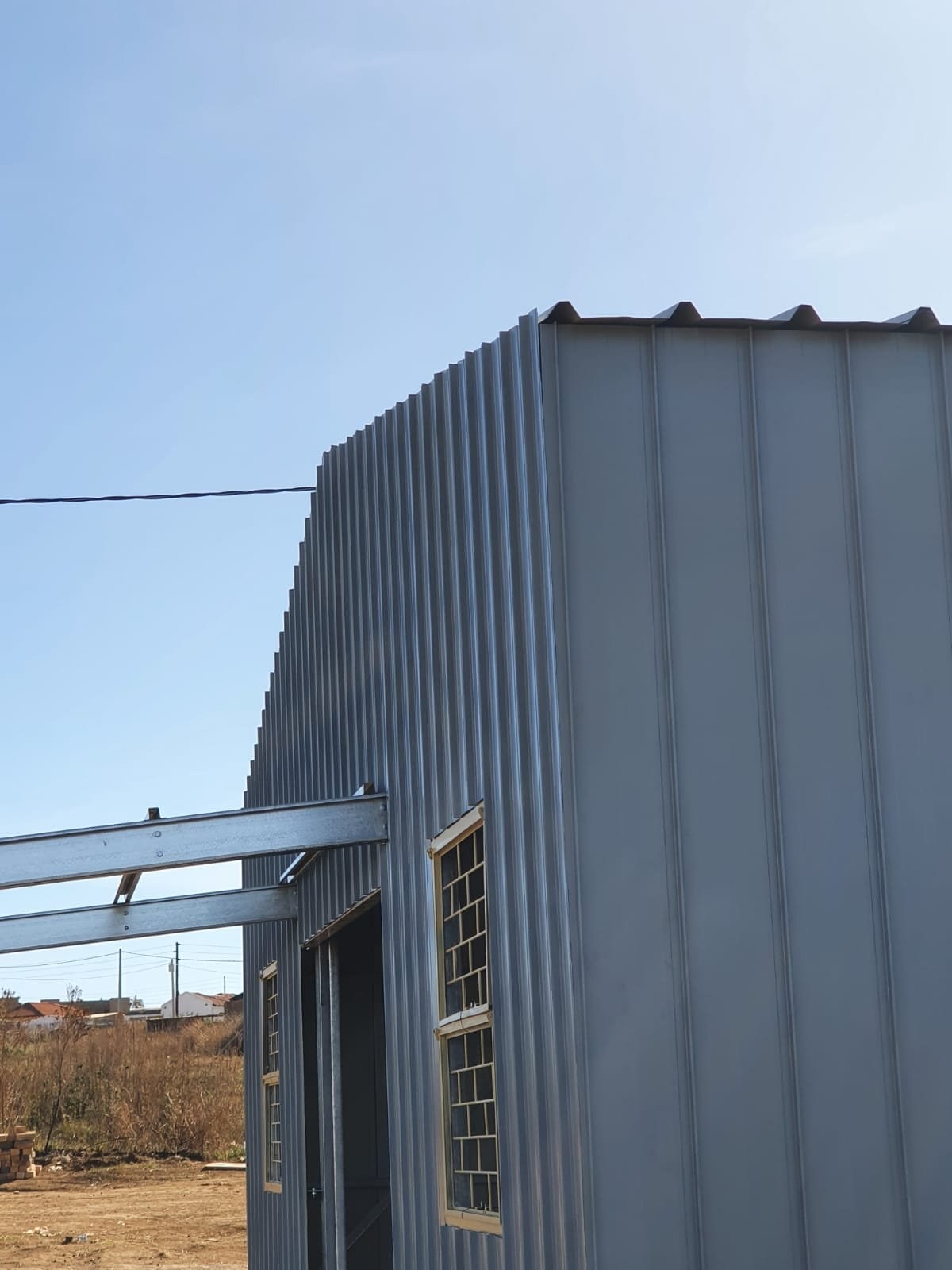 Curved gable-end corner of a steel-clad building with door and window openings