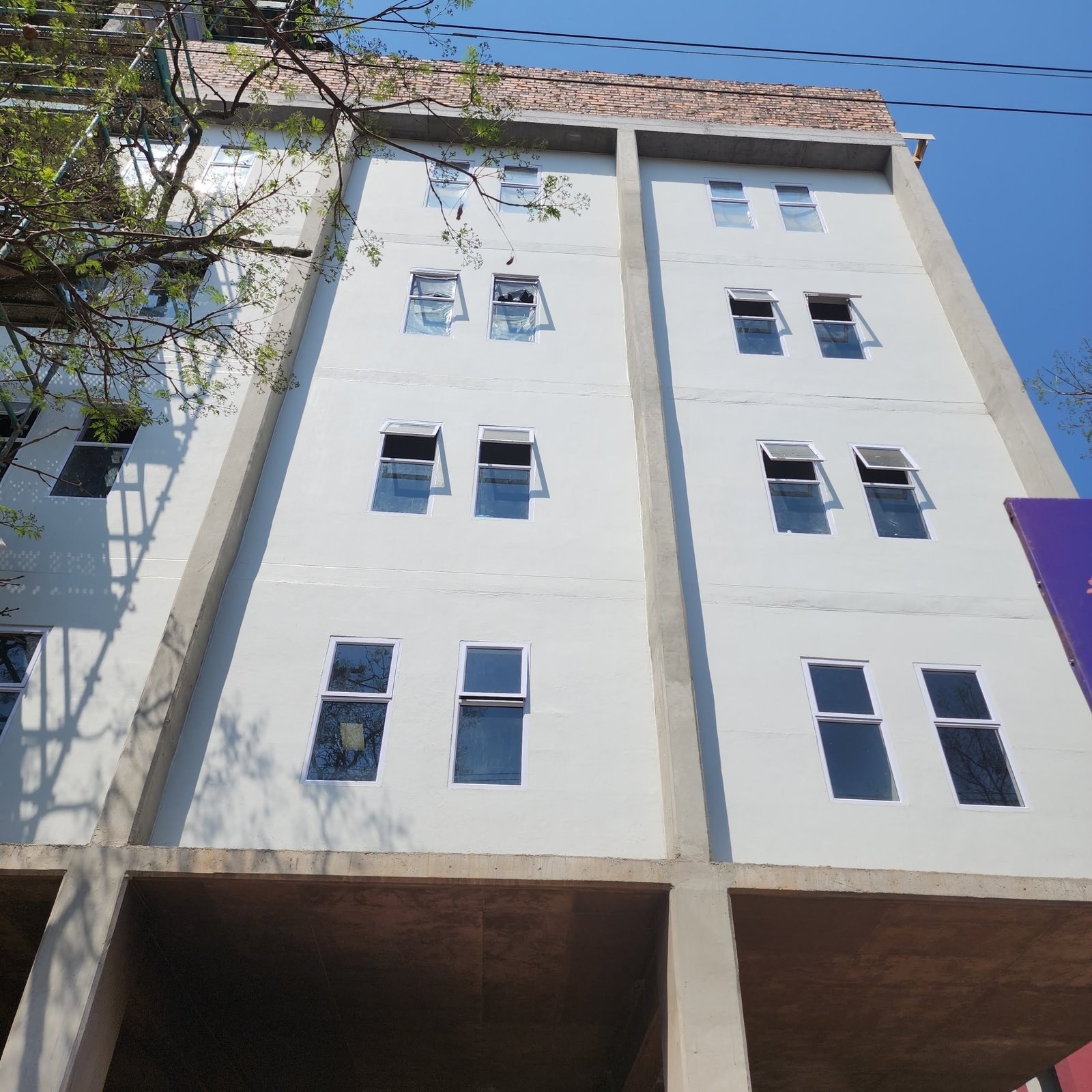 Completed multi-storey building with painted block facade and window units installed.