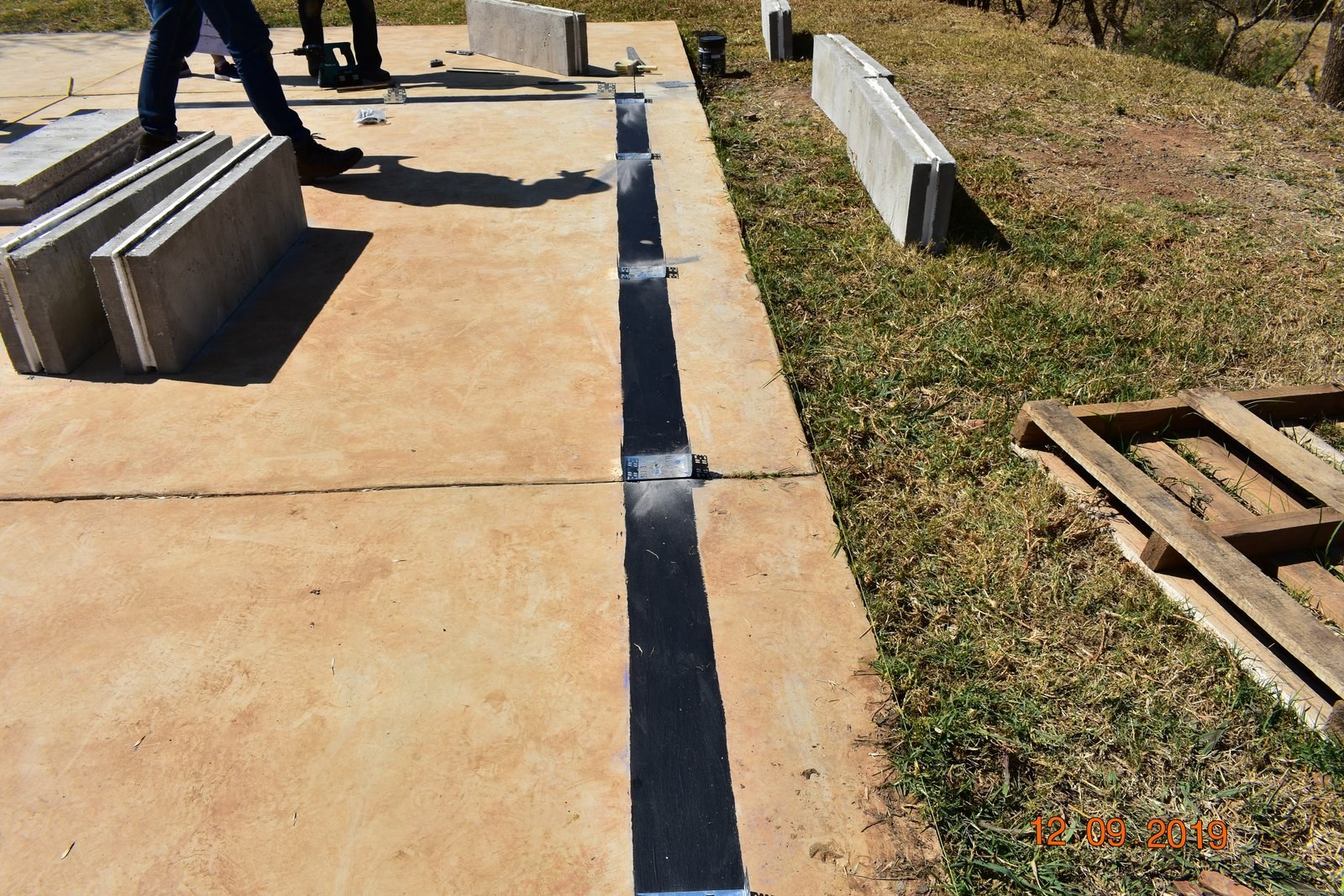 Close-up of a black insulation strip embedded along a slab edge with steel angle brackets fixed at intervals.