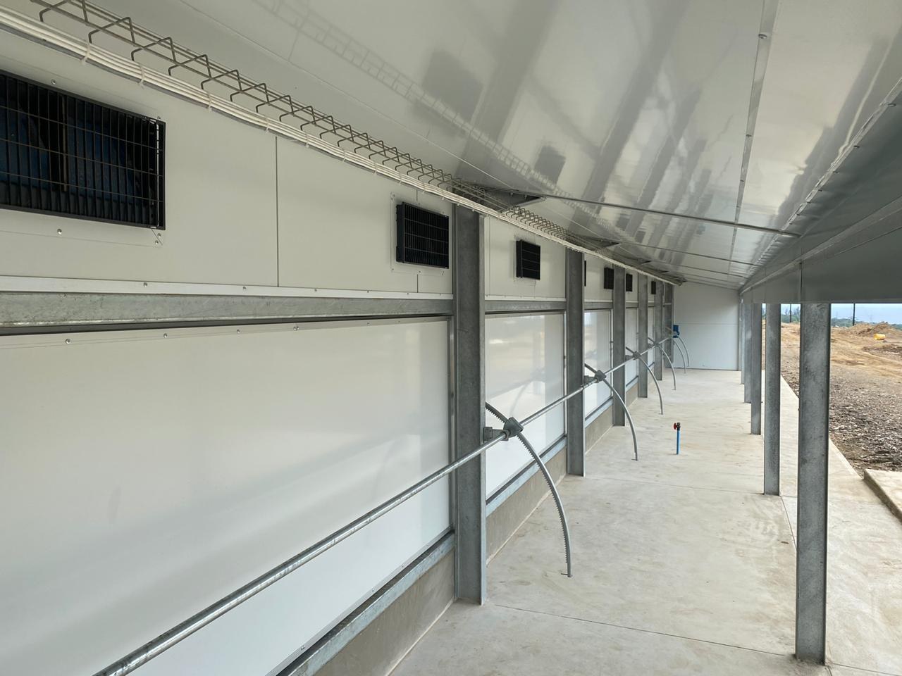 Inside the house, looking along the sidewall. The panel sits on the concrete plinth on a base channel; a horizontal capping runs between the panel courses.