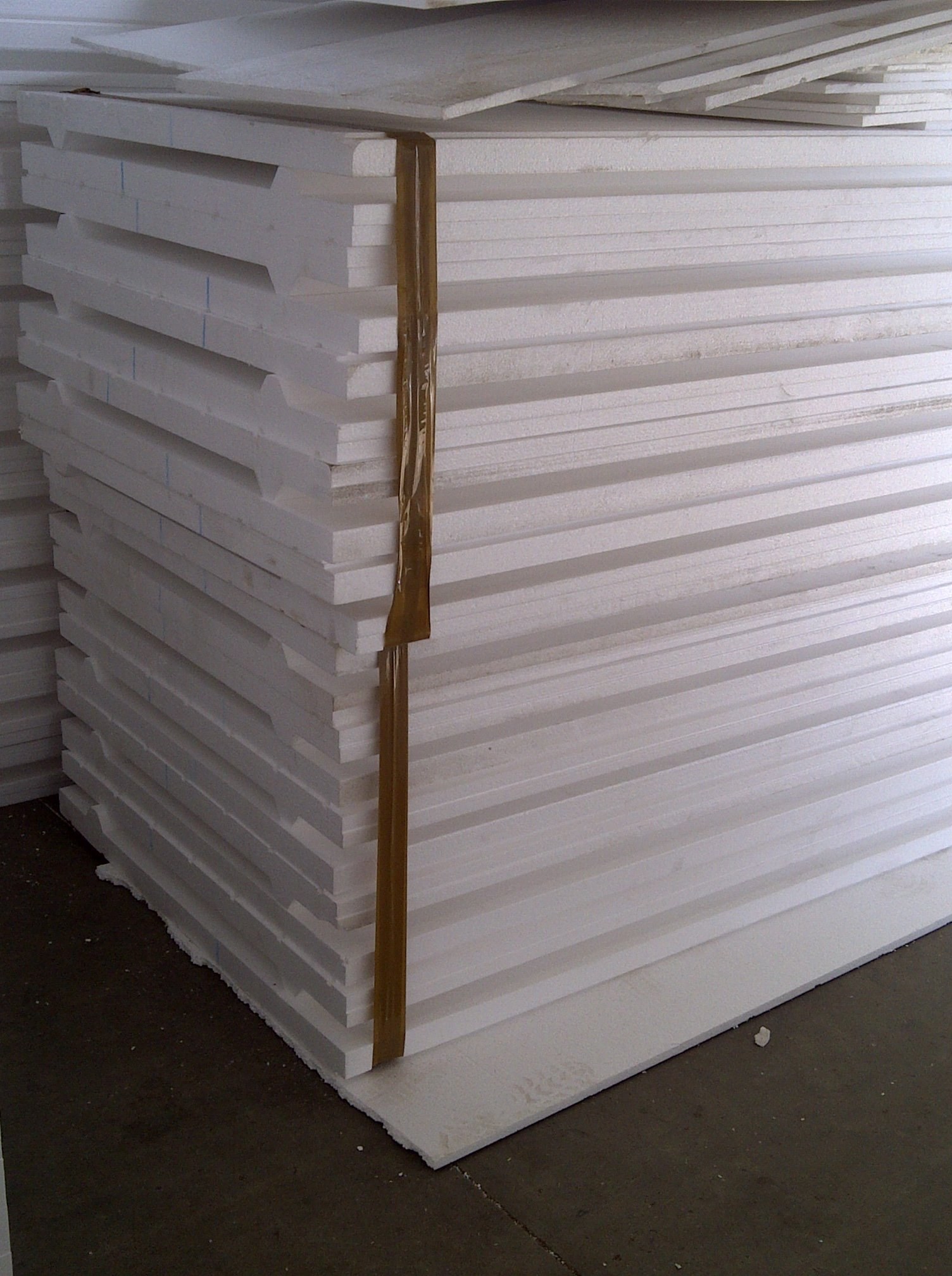 Close-up corner of a stacked panel showing the tongue-and-groove edge profile, factory warehouse