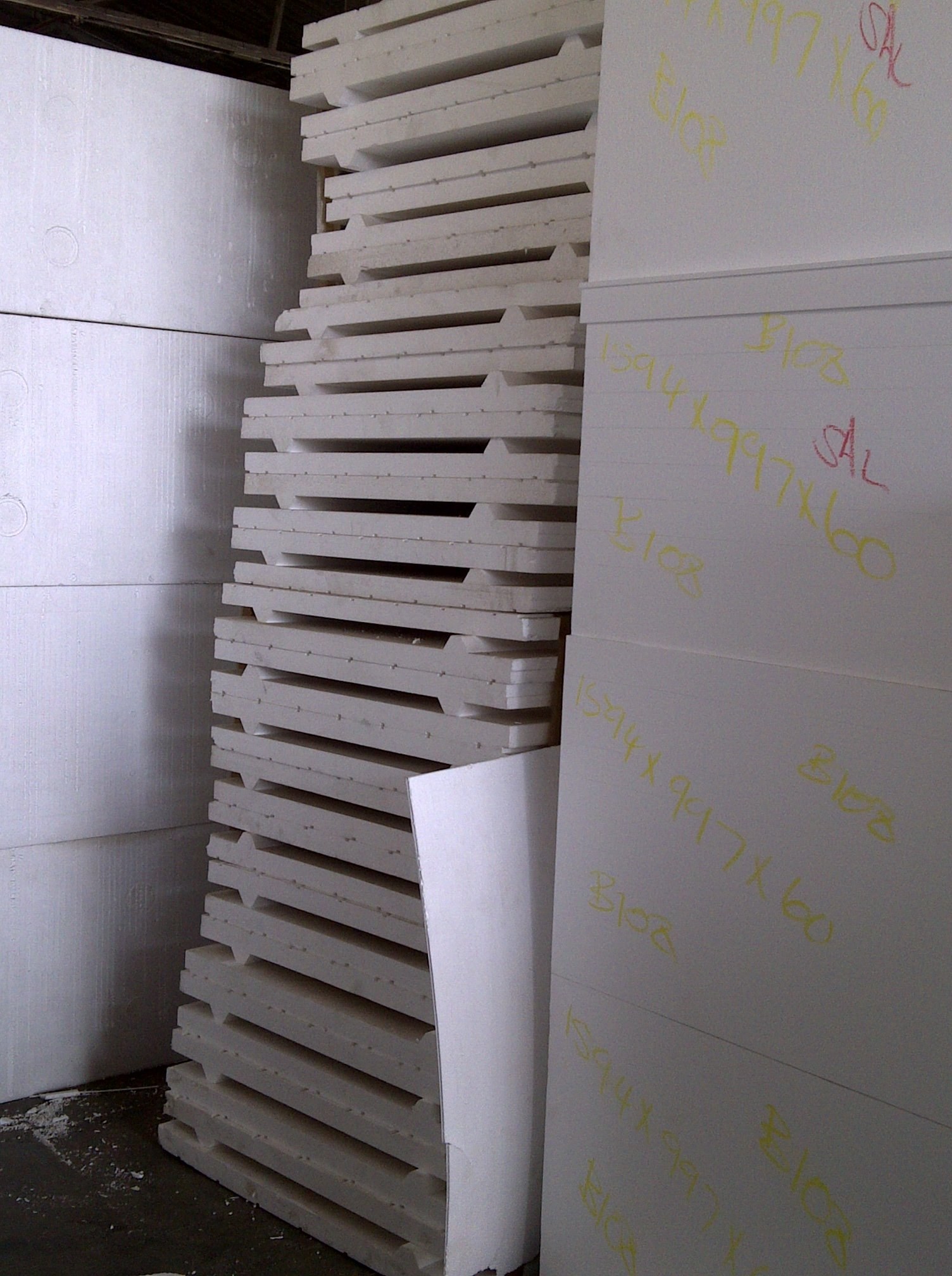 Panel edges marked by hand with size and batch numbers in the warehouse