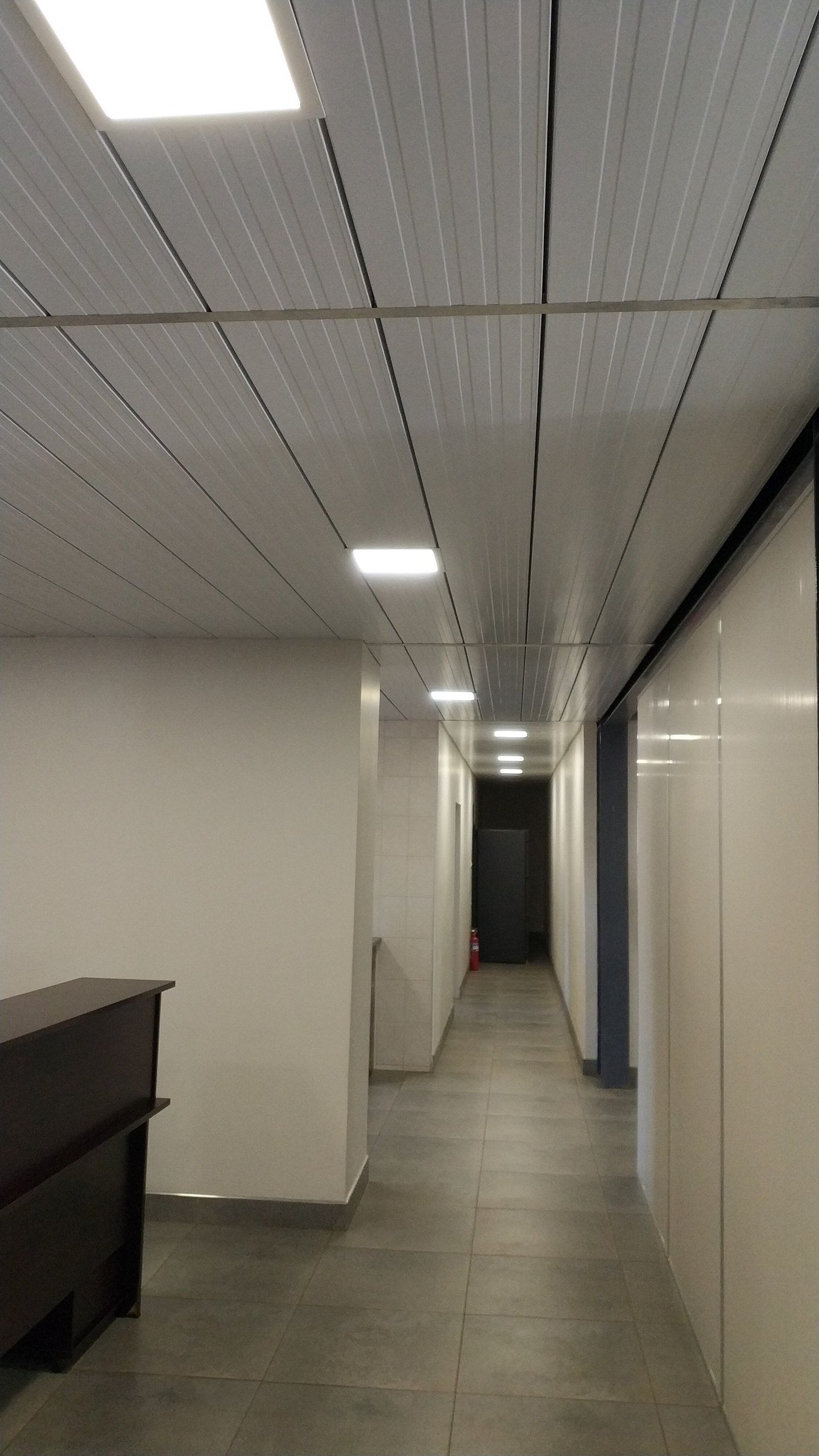 Panel ceiling with recessed downlights along an office corridor