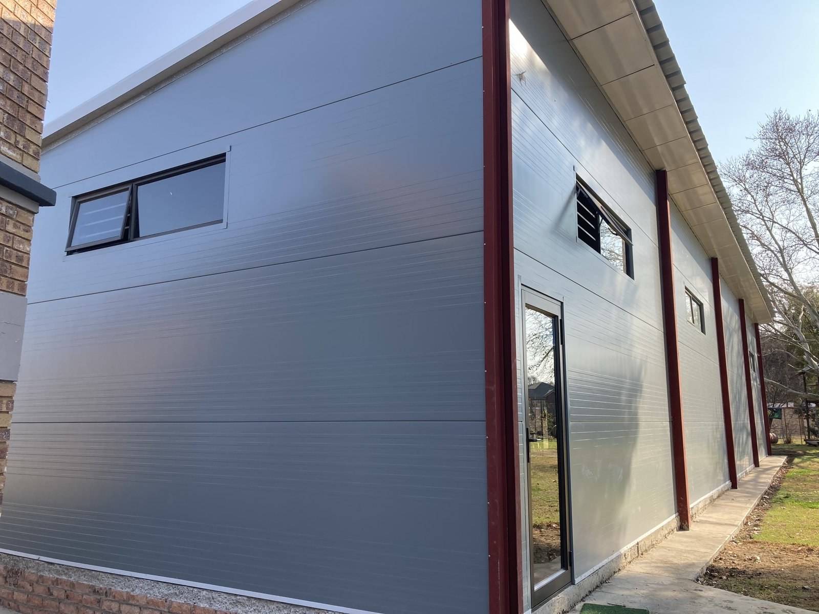 Long wall elevation of a building clad in wall panels, with columns and window openings along its length