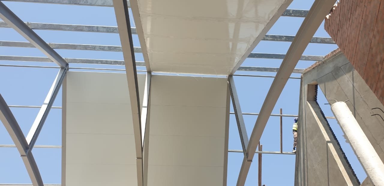 Worker on scaffolding beside a curved vaulted soffit panel installation