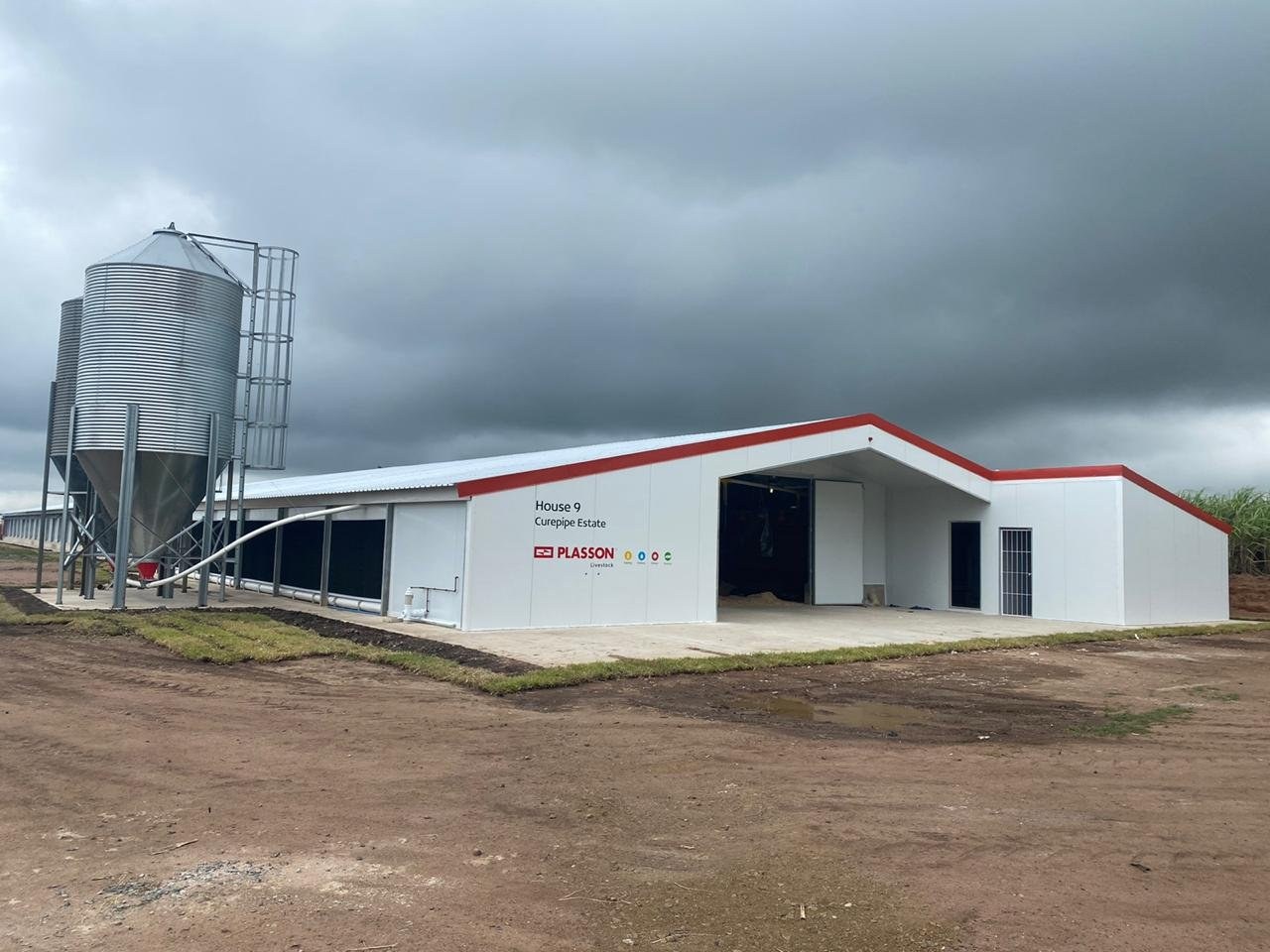 Poultry house exterior clad in wall panels, with feed silo and site signage