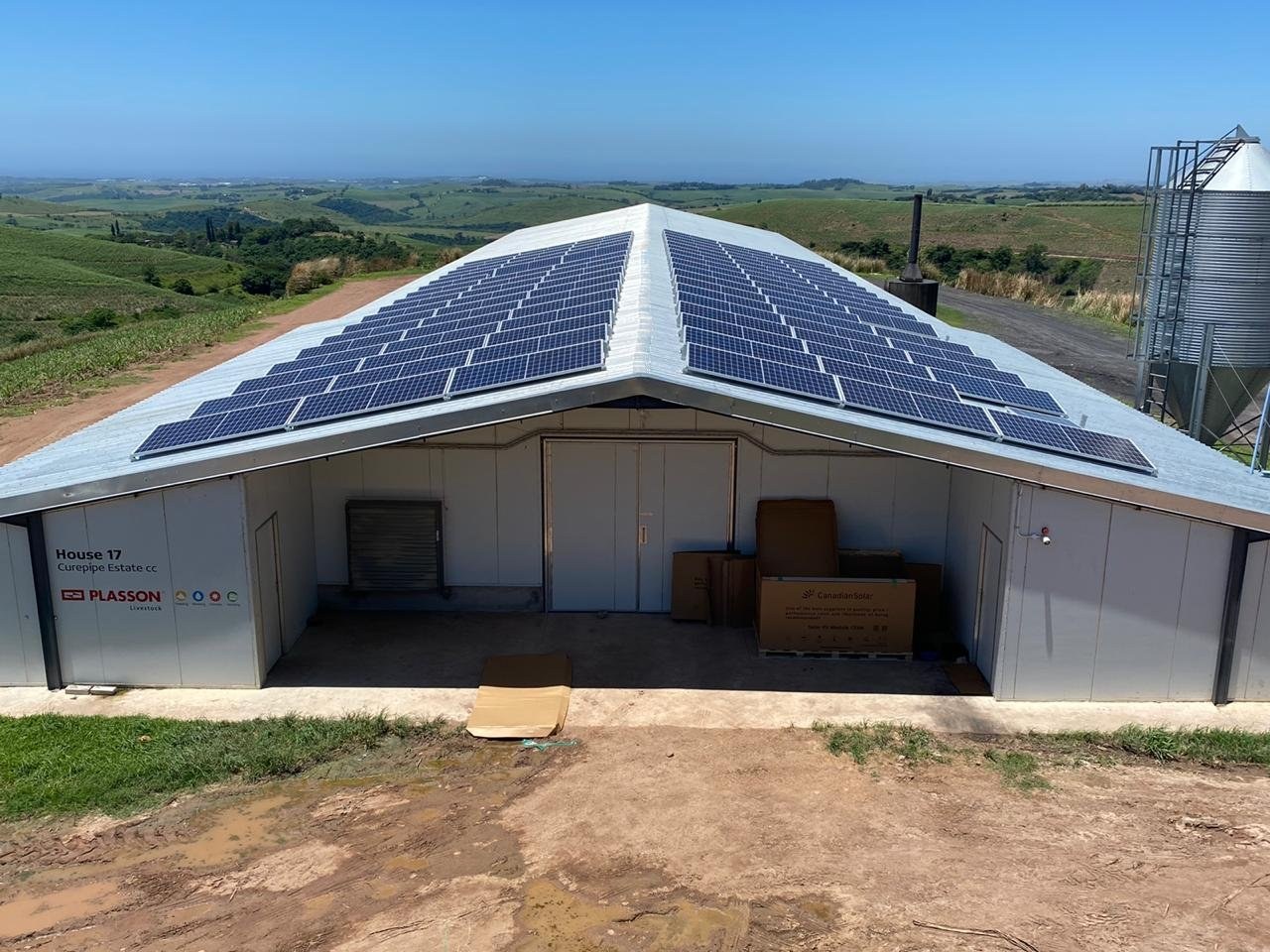 Poultry house gable end with wall panels and solar panels mounted on the roof