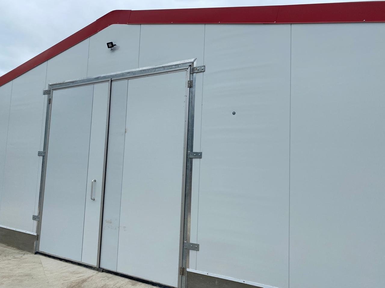 Double door set into an insulated wall panel, roof edge trim above