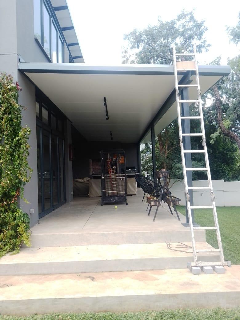 Underside of a flat LiteSpan panel patio canopy, finished ceiling visible from below with the access ladder still in place