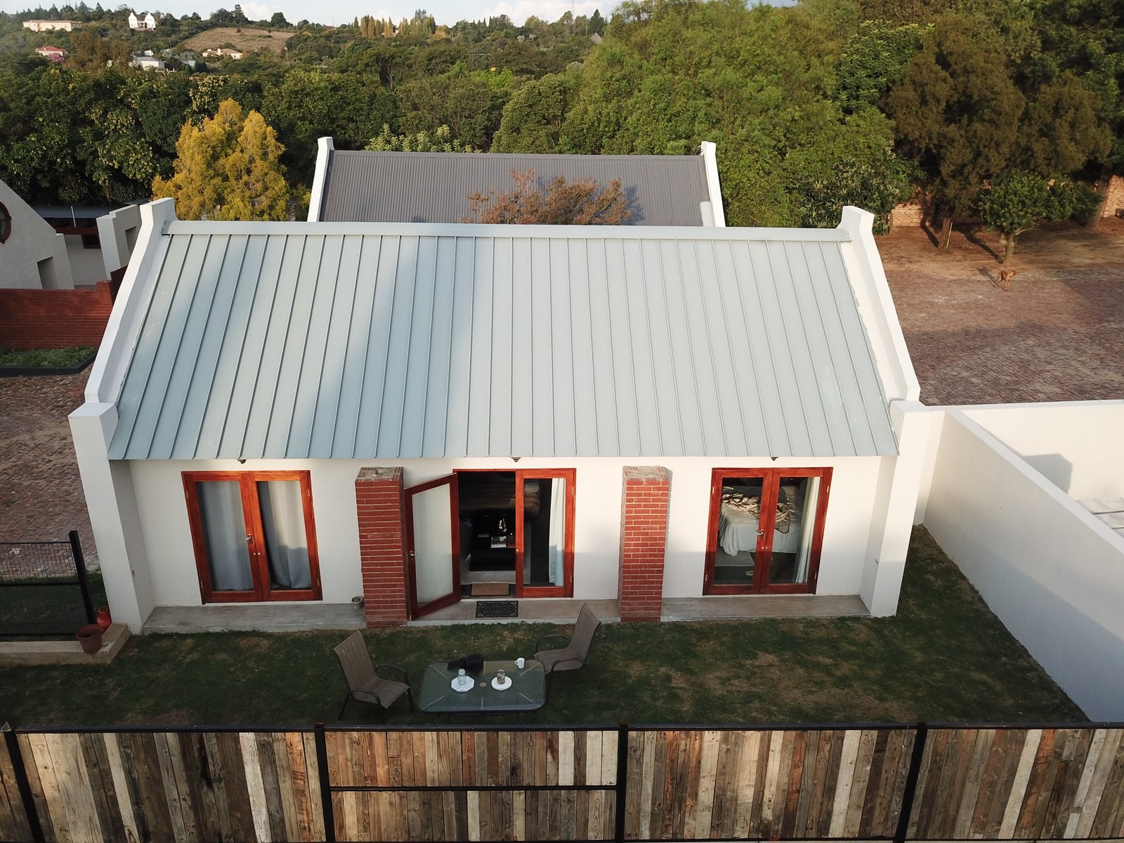Aerial view of a Cape Dutch style cottage with a completed standing-seam roof and gabled parapets