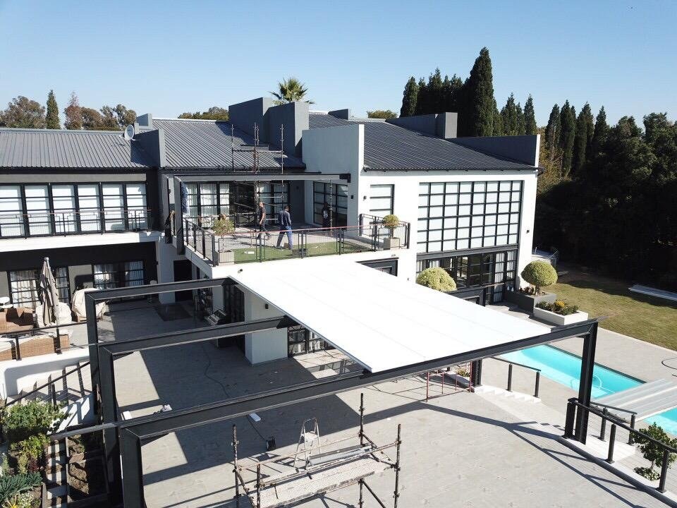 Aerial view of the same canopy structure mid-installation, roof sheeting fitted over the steel frame with scaffolding still in place below