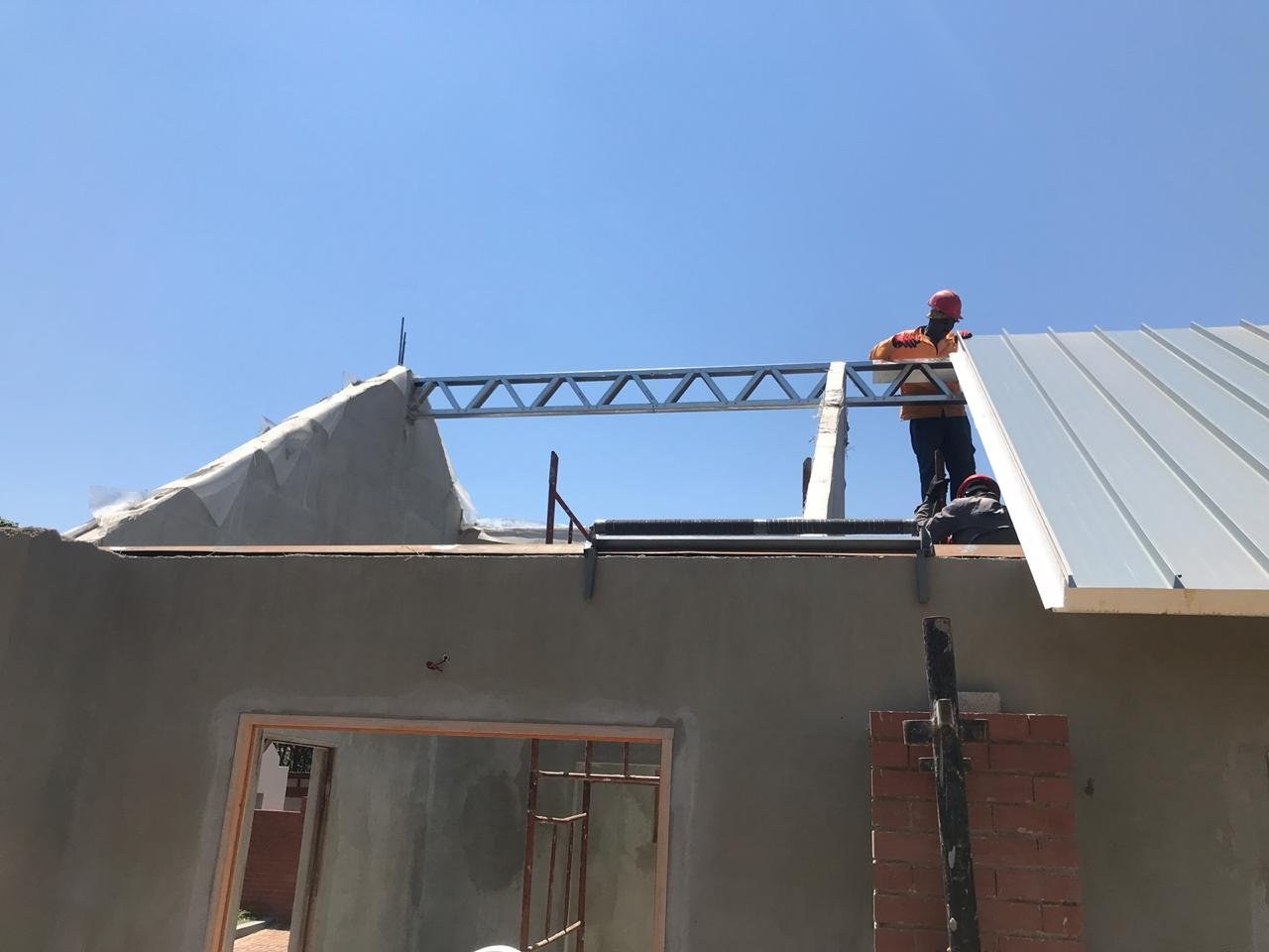 Steel purlin truss being fitted at a gable end before roof sheeting is completed