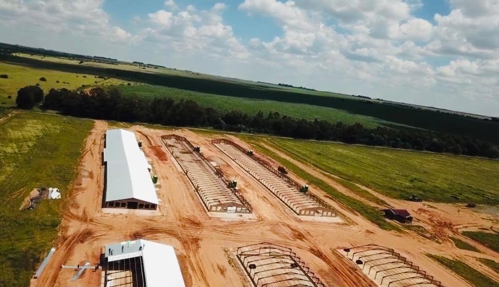 Aerial view of poultry houses under construction, steel roof frames alongside a completed building